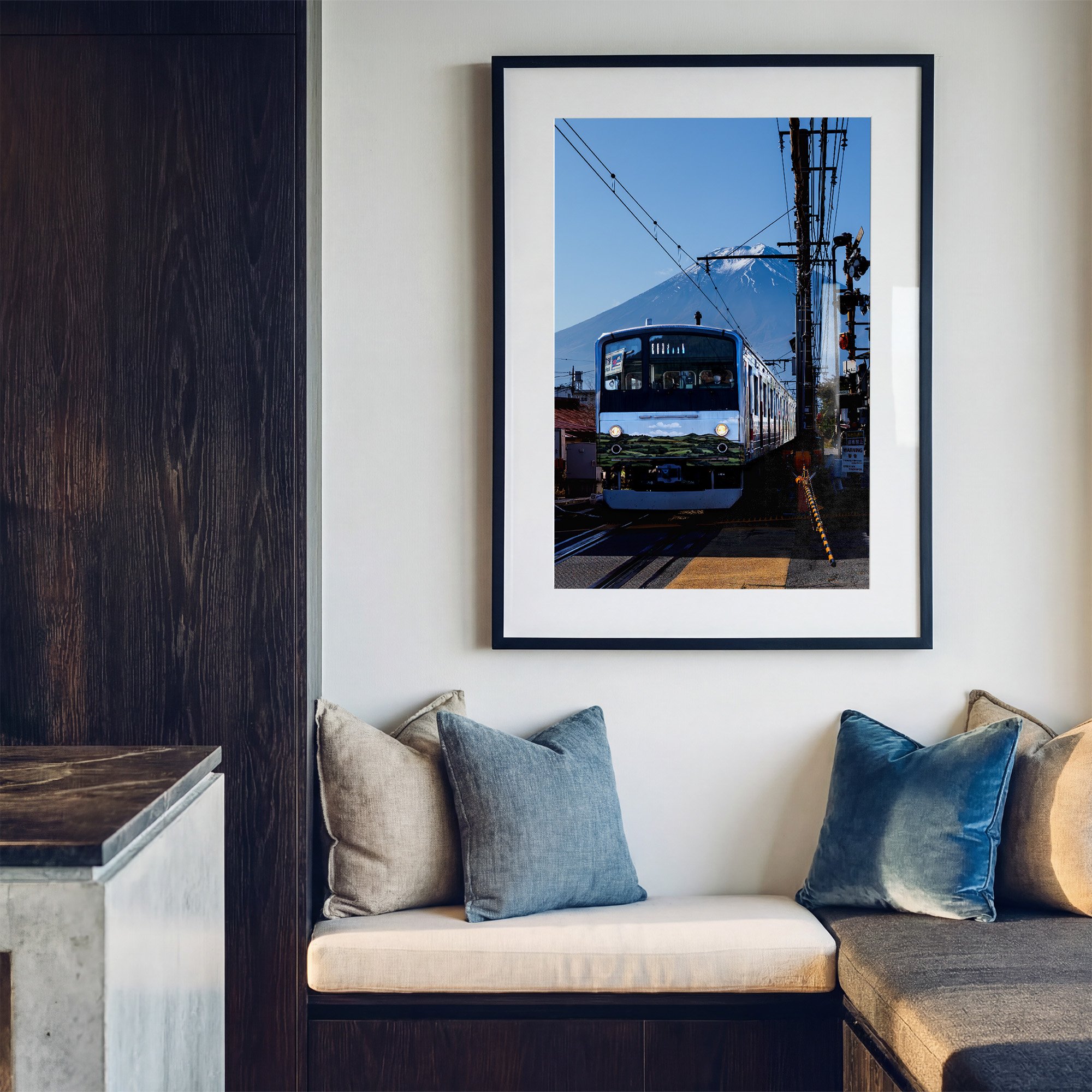 Mount Fuji photography print featuring a Japanese train at a railway crossing, displayed in a black frame with white mat above a contemporary window seat.
