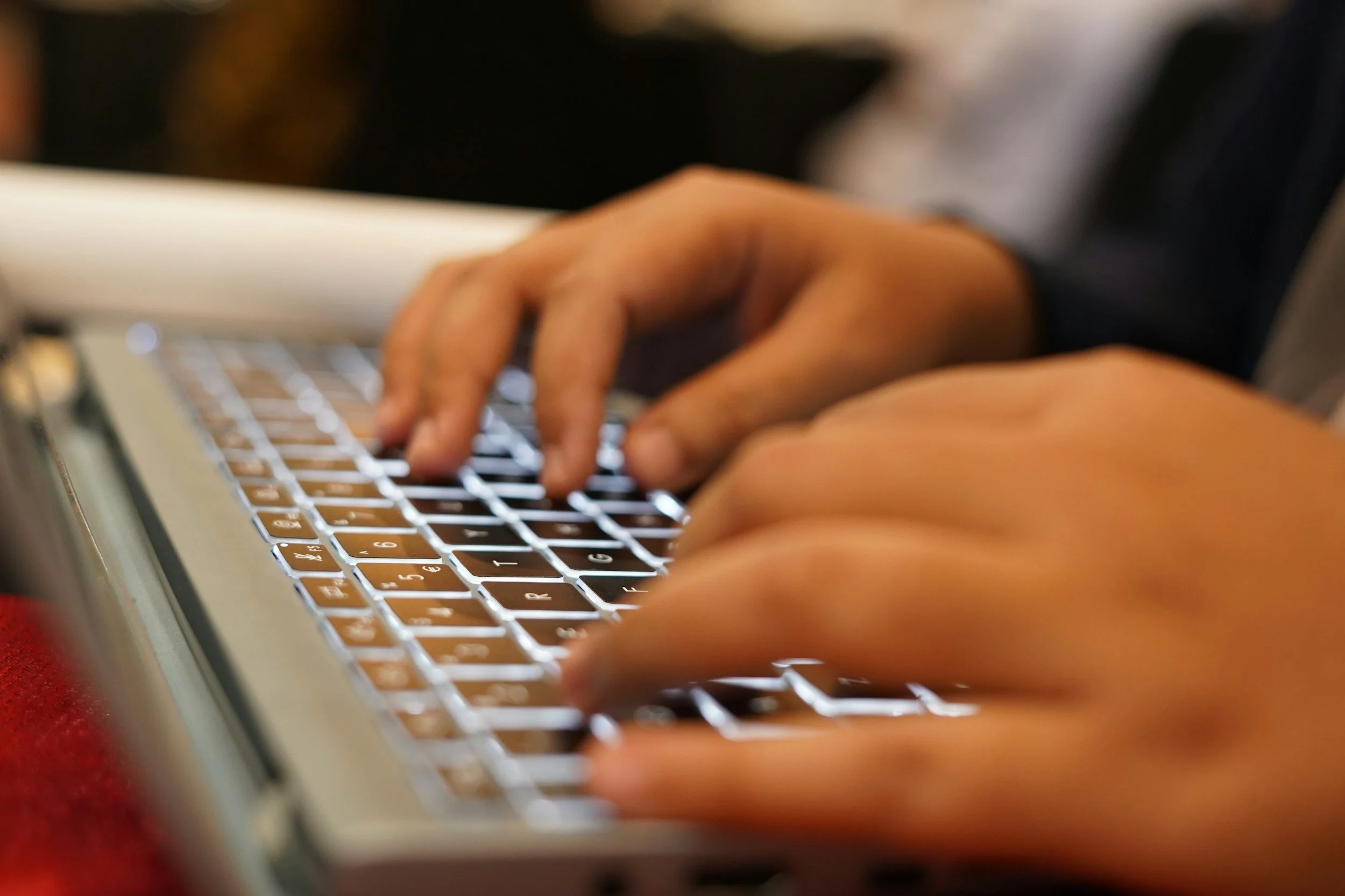 Close-up of hands typing on a laptop keyboard.