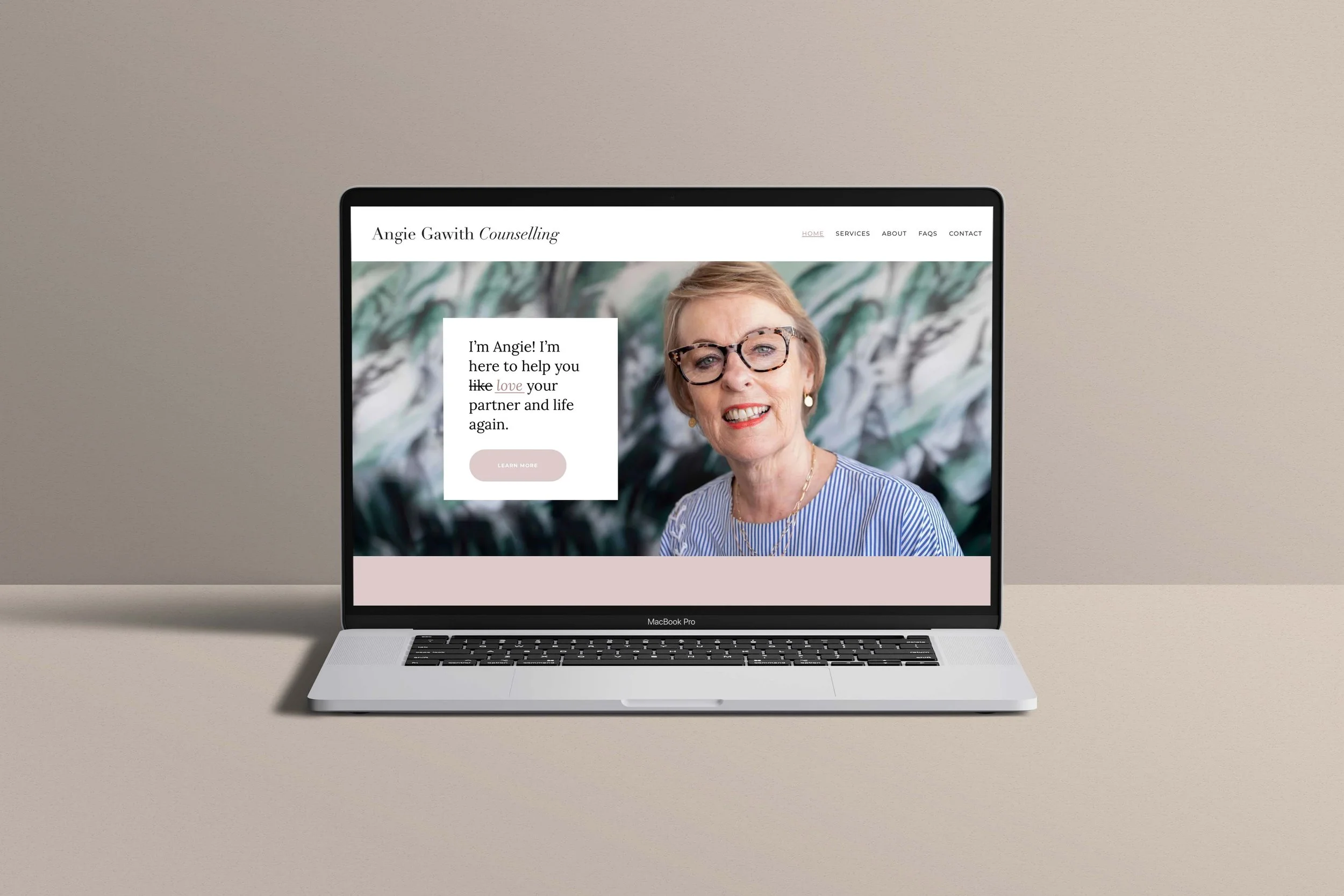 Laptop displaying a counseling website with a photo of a smiling woman wearing glasses and a striped shirt.