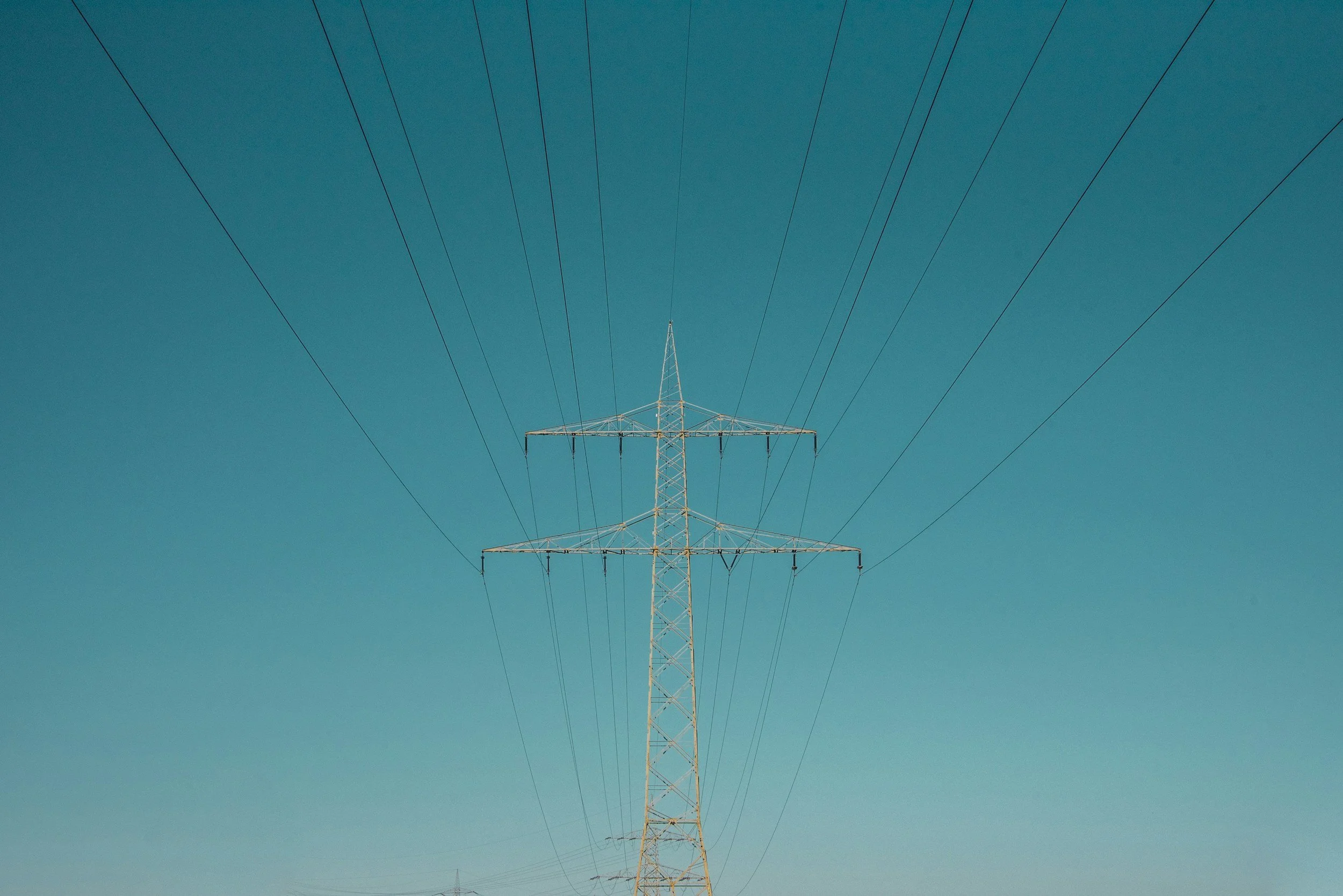 Electric power line tower against a clear blue sky.