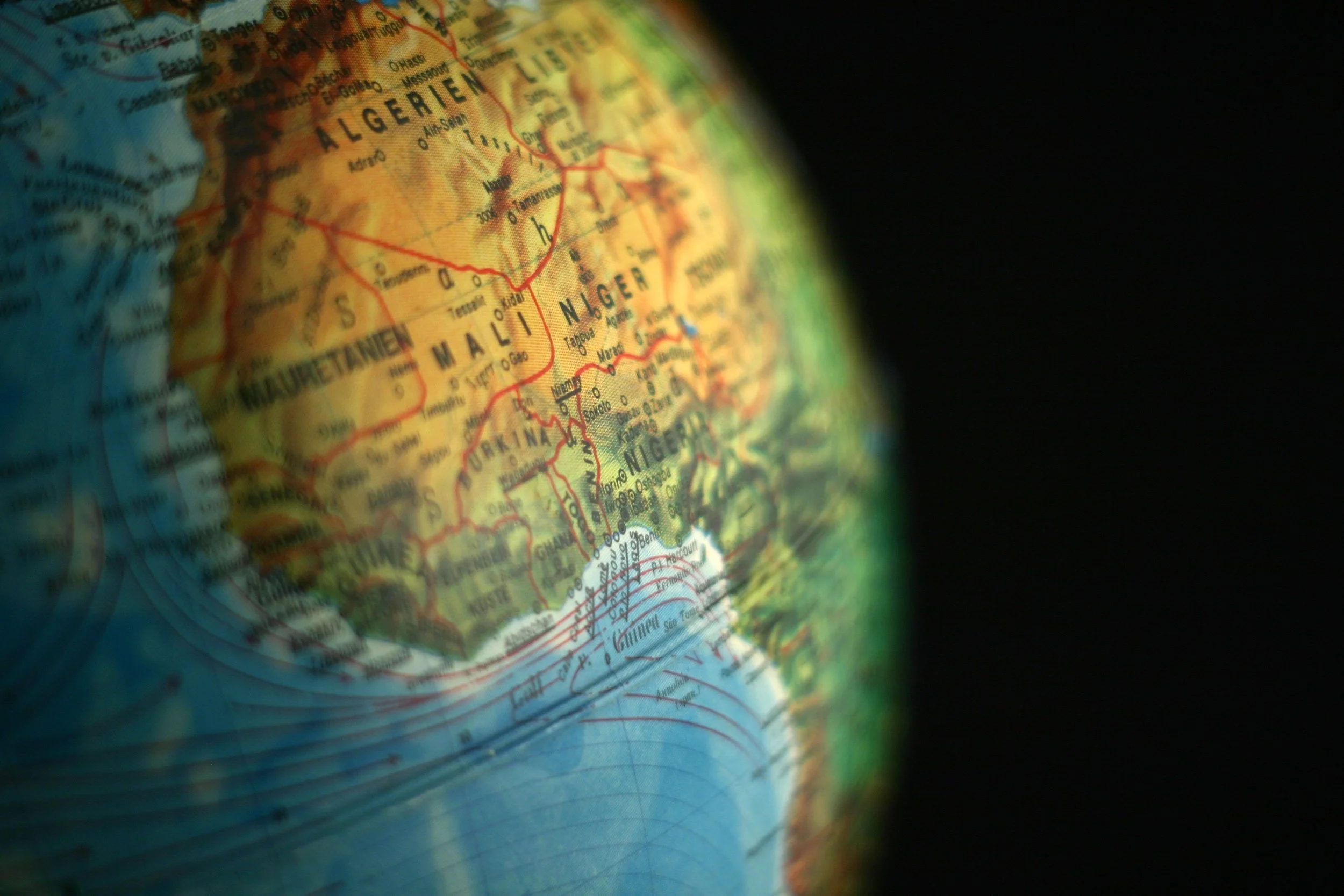 Close-up of a globe focusing on the countries of Algeria, Niger, Mali, Mauritania, and Libya with a black background.