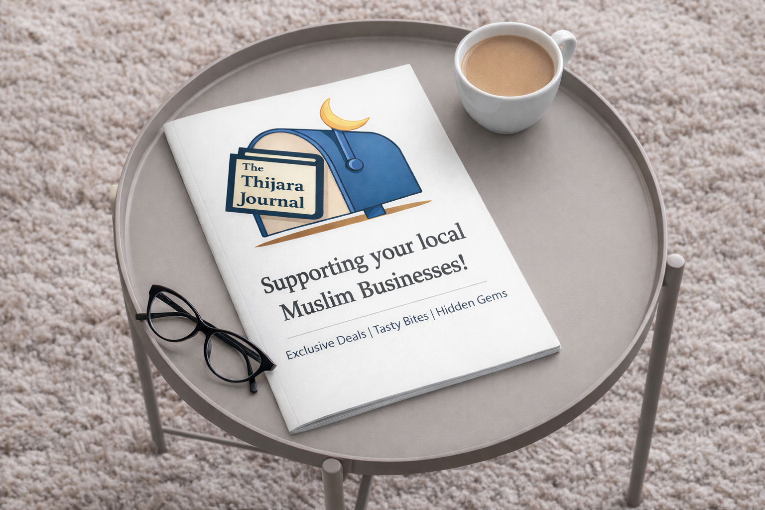 A round tray on a beige carpet holds a magazine titled "The Thijara Journal" supporting local Muslim businesses, a pair of black glasses, and a white mug filled with coffee.