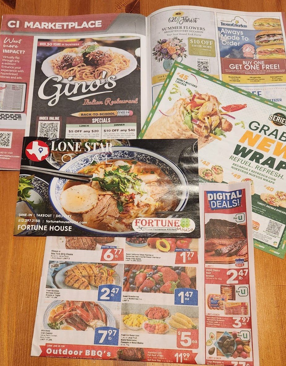 Collection of multiple restaurant and grocery store advertisements on a wooden surface, featuring offers for food and discounts.