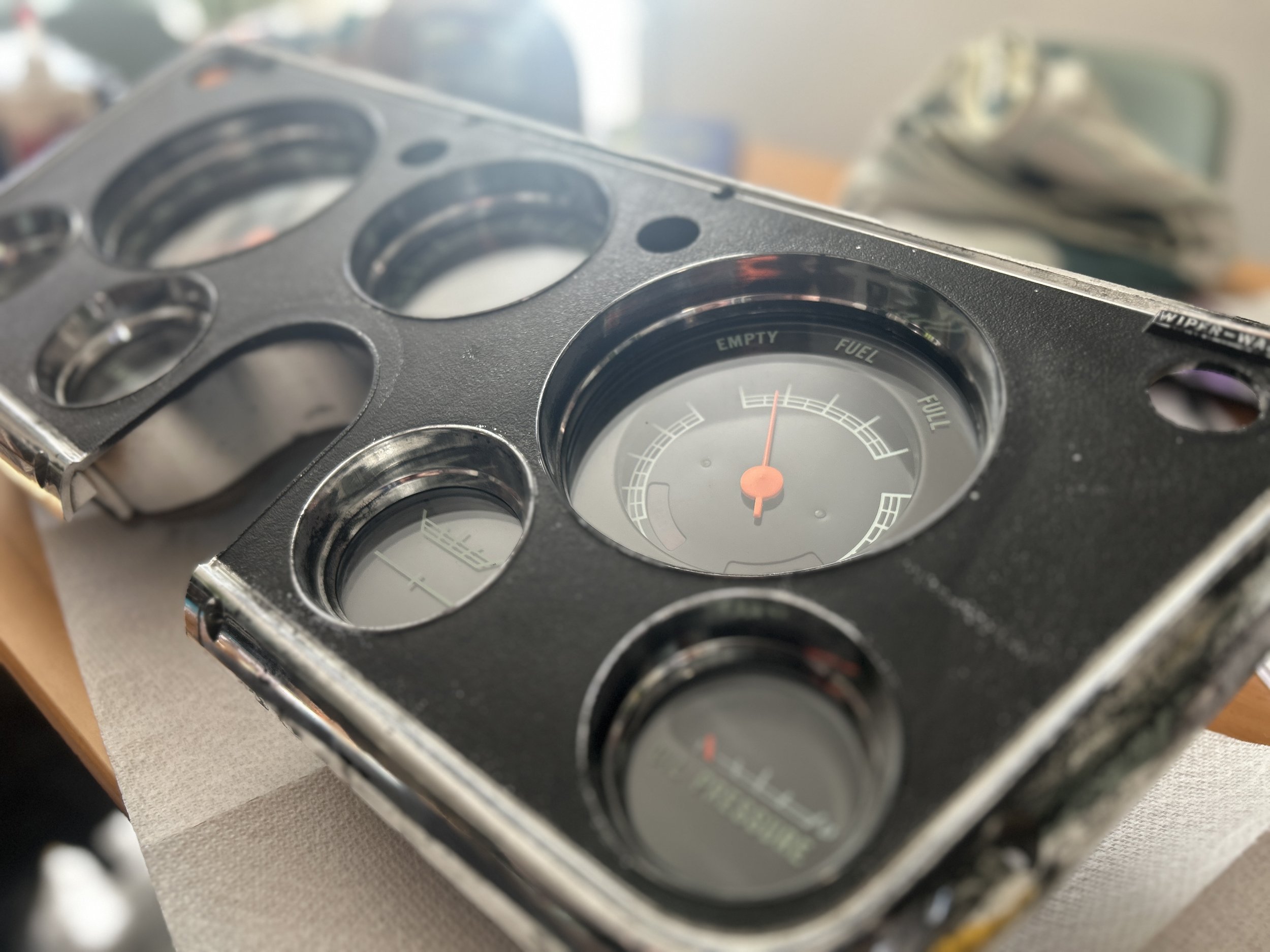 Close-up of a car dashboard instrument cluster with empty circular gauges and a fuel gauge showing almost empty.