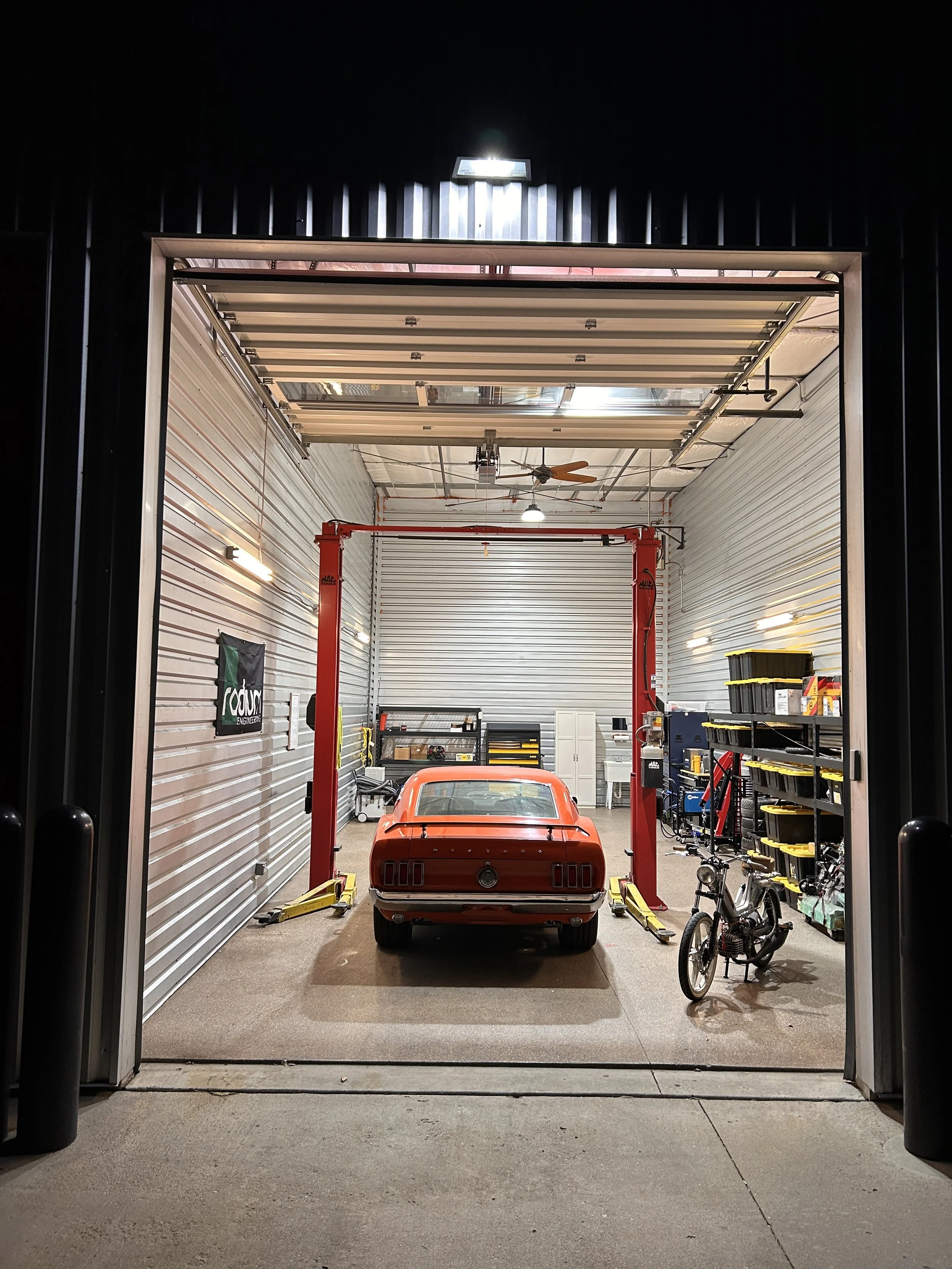 Inside a garage with a red car on a lift, a bicycle, and various tools and equipment.