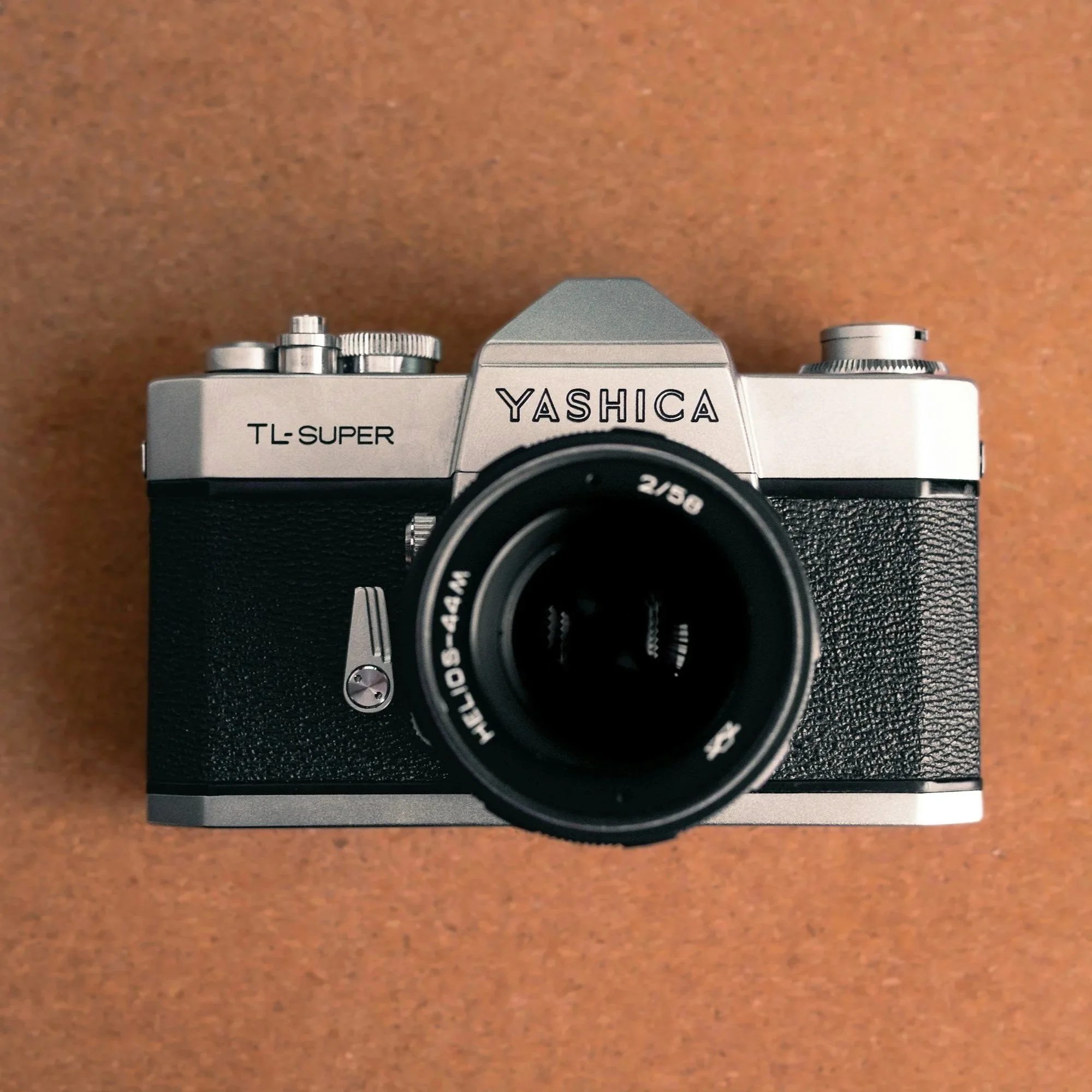 Top view of a vintage yashica camera with a lens on a brown surface.