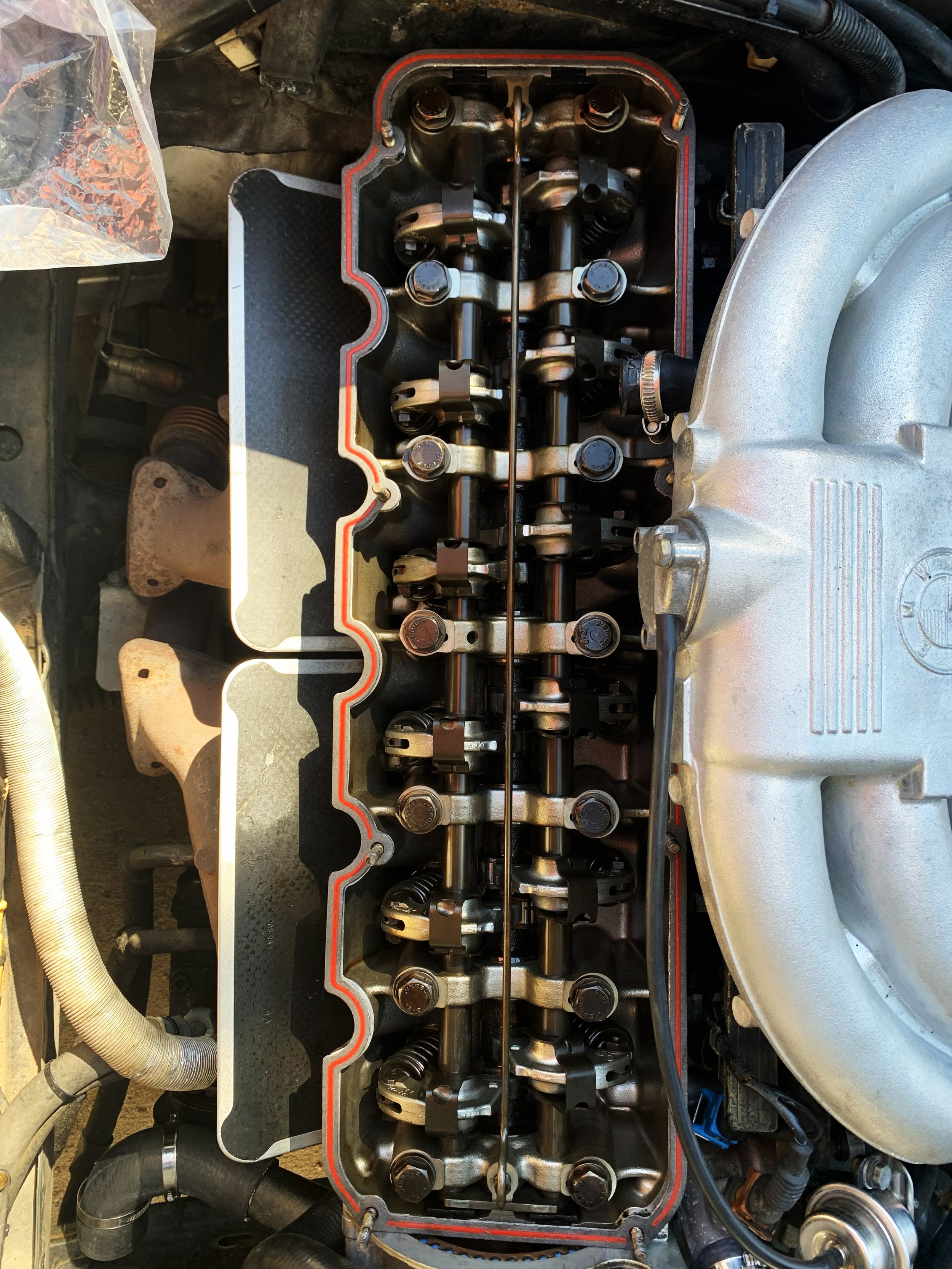 Close-up view of a car engine with an open valve cover, showing the rocker arms and valve springs.