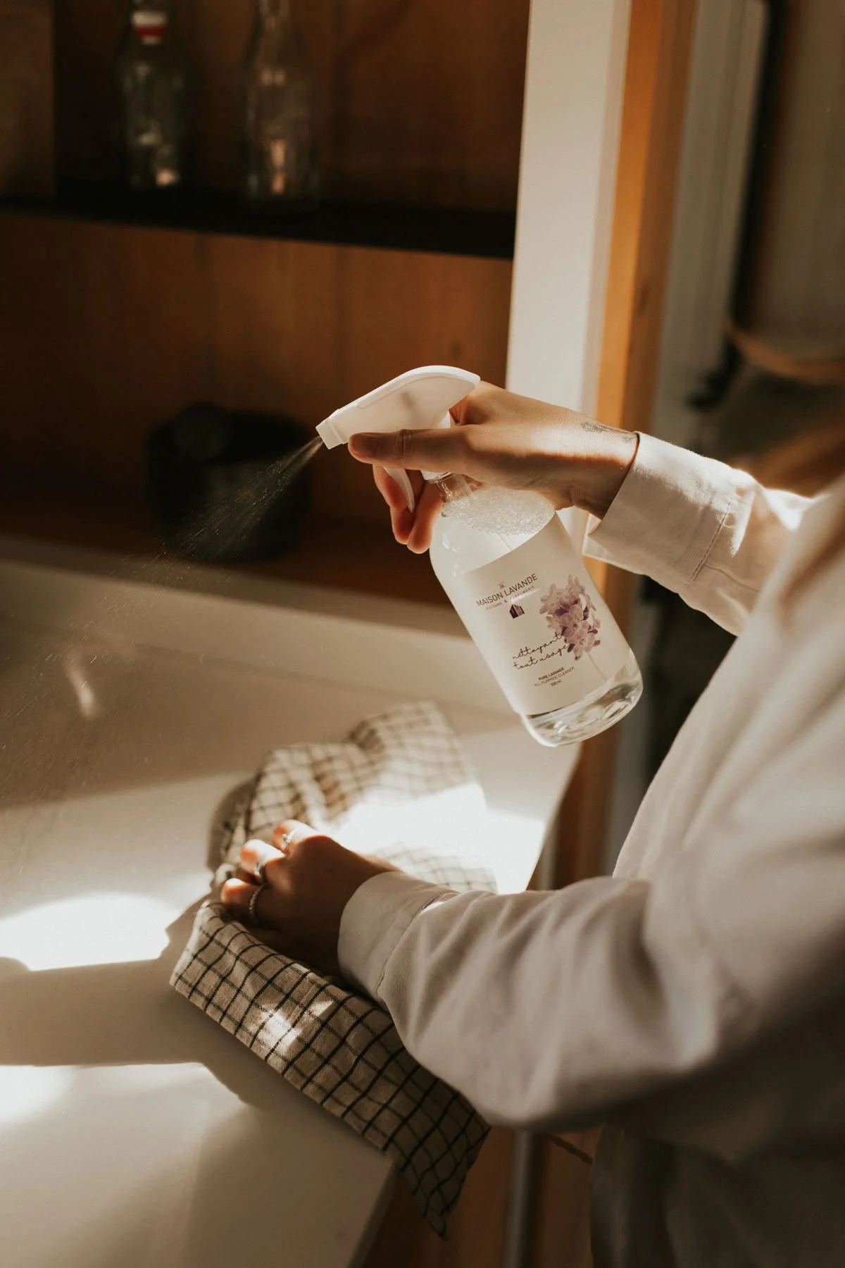 Person spray-cleaning a kitchen countertop with a spray bottle.