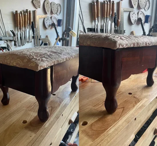 A wooden bench with a padded, floral upholstery cushion on top. The bench has curved, dark wood legs. In the background, there are various woodworking tools hanging on a wall and a worktable.