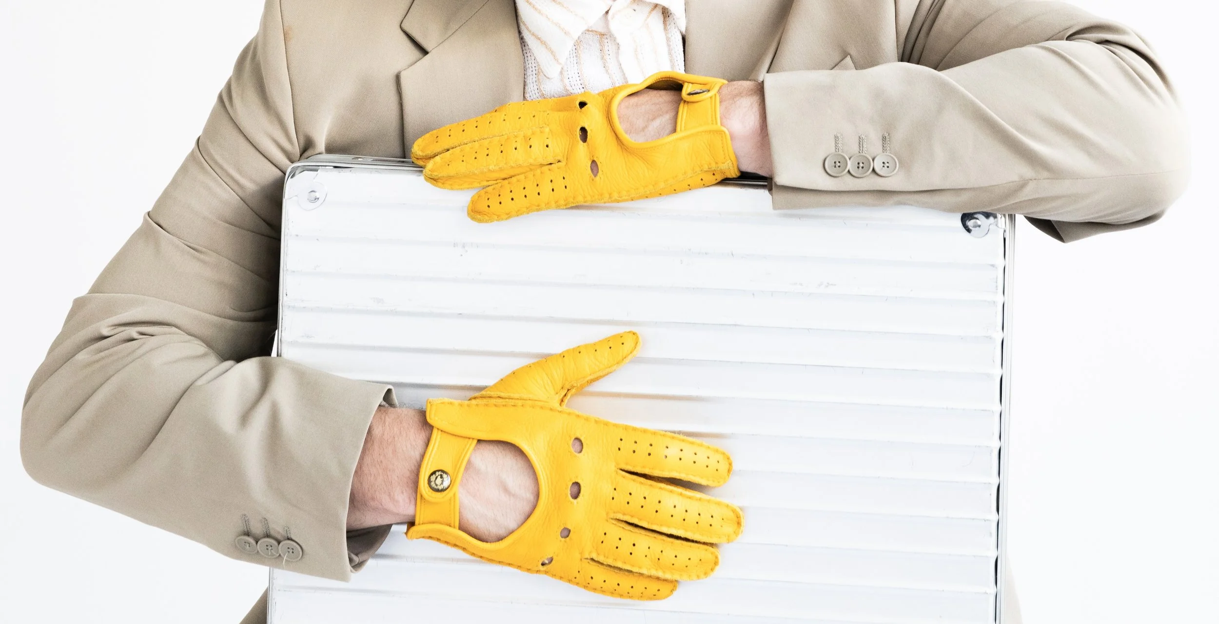 Person wearing a beige suit holding a white object with yellow gardening gloves, on a white background.