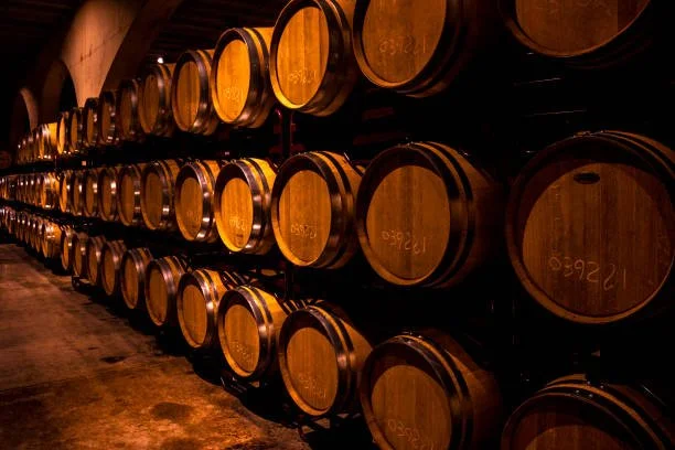Rows of wooden wine barrels stored on racks in a wine cellar.