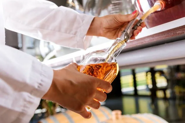 Person pouring rosé wine from a bottle into a wine glass.