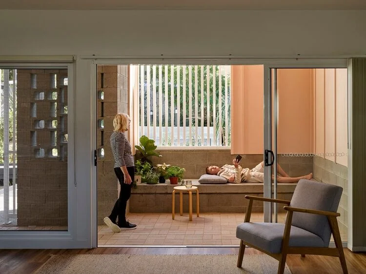 View from the living area to private outdoor space through large sliding doors. A woman and child are in the private outdoor space chatting.