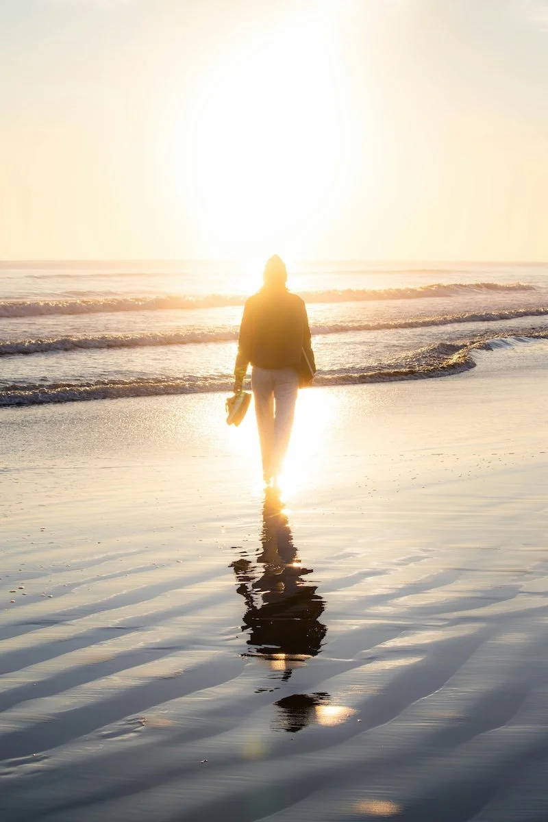 Person walking barefoot at sunset, symbolising balance, reflection and holistic wellbeing with Rebecca McGrath Naturopath.