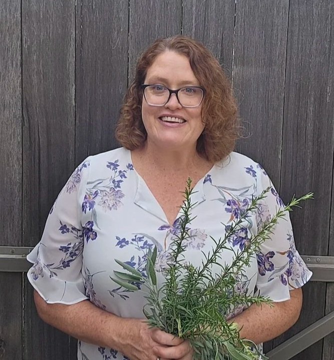 Rebecca McGrath, qualified naturopath in Sydney, holding fresh herbs and smiling, representing personalised and evidence-informed naturopathic care.