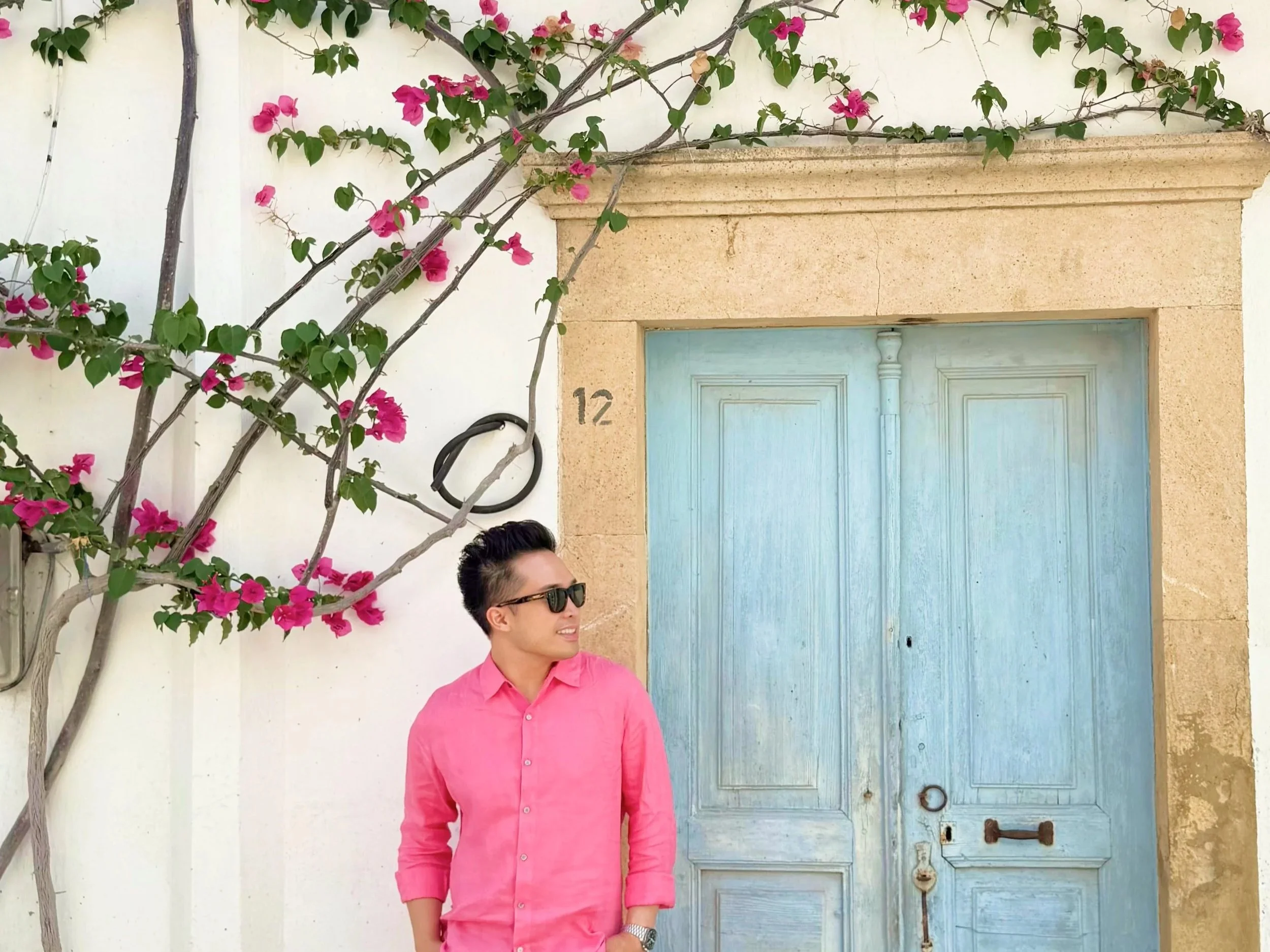  Pink bougainvillea over a whitewashed house and a weathered blue door on Patmos, the Dodecanese island known for the Cave of the Apocalypse and the Monastery of Saint John. 