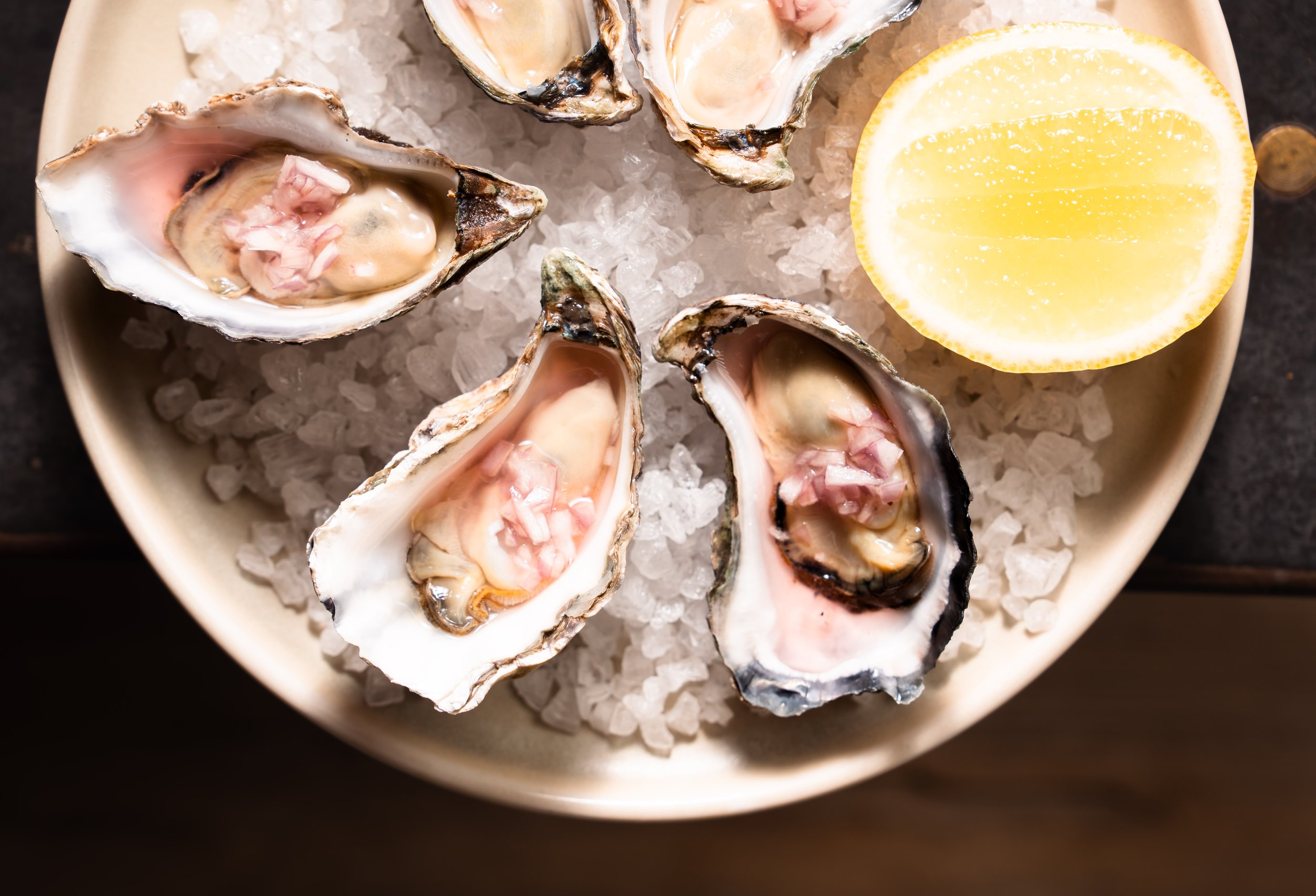 Fresh oysters on ice with chopped onions, served with a lemon half.