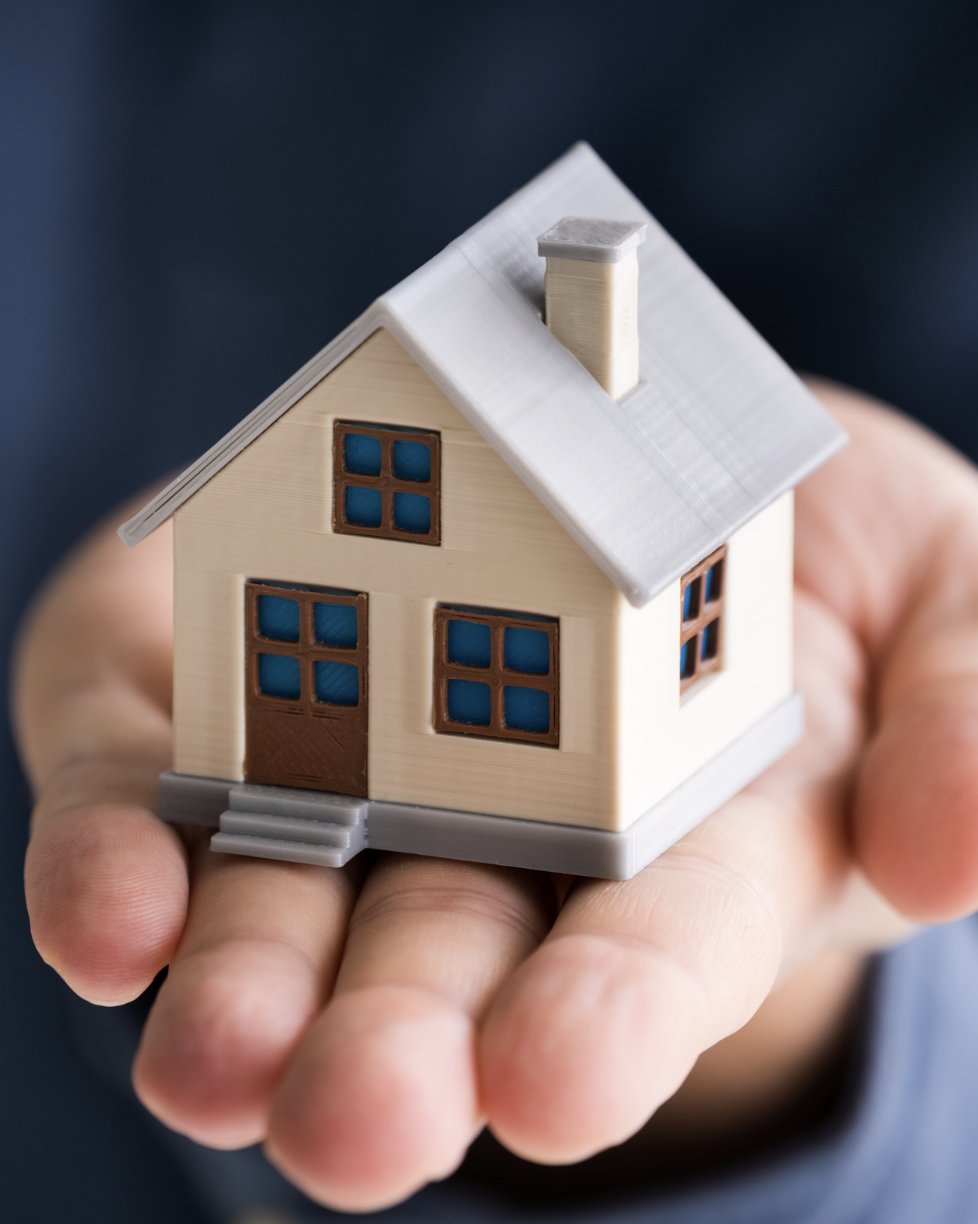 Miniature model of a house being held in a person's hand.