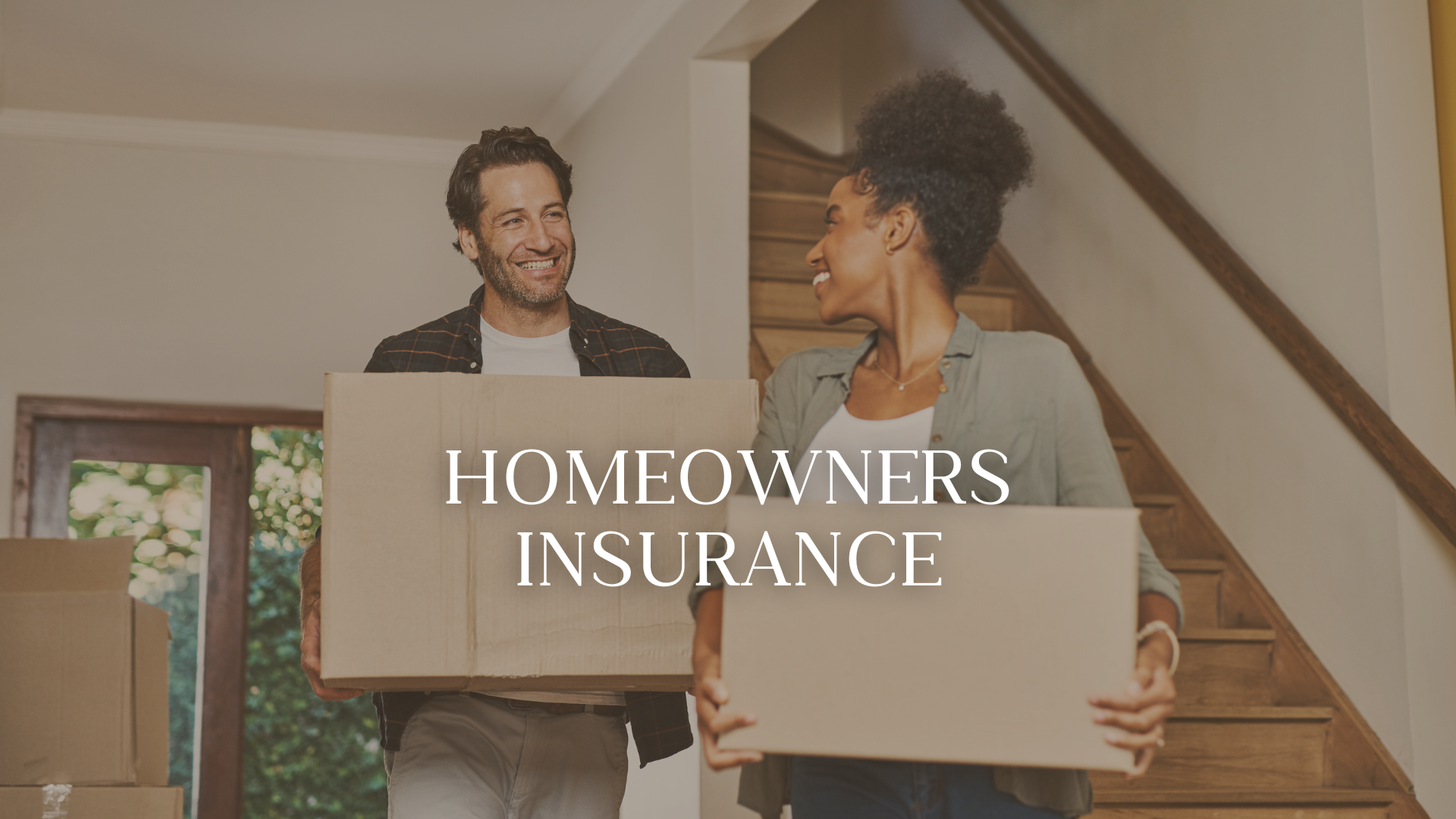 Two people carrying moving boxes inside a home with stairs in the background, smiling at each other, text overlay says 'Homeowners Insurance'.