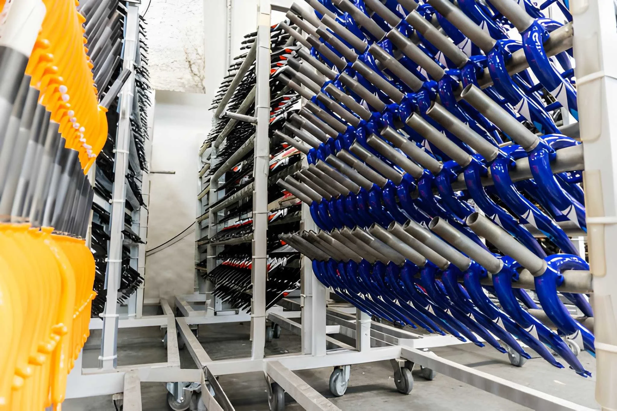 Stacked wire racks holding blue and silver inline skates and orange skate helmets in a storage room.