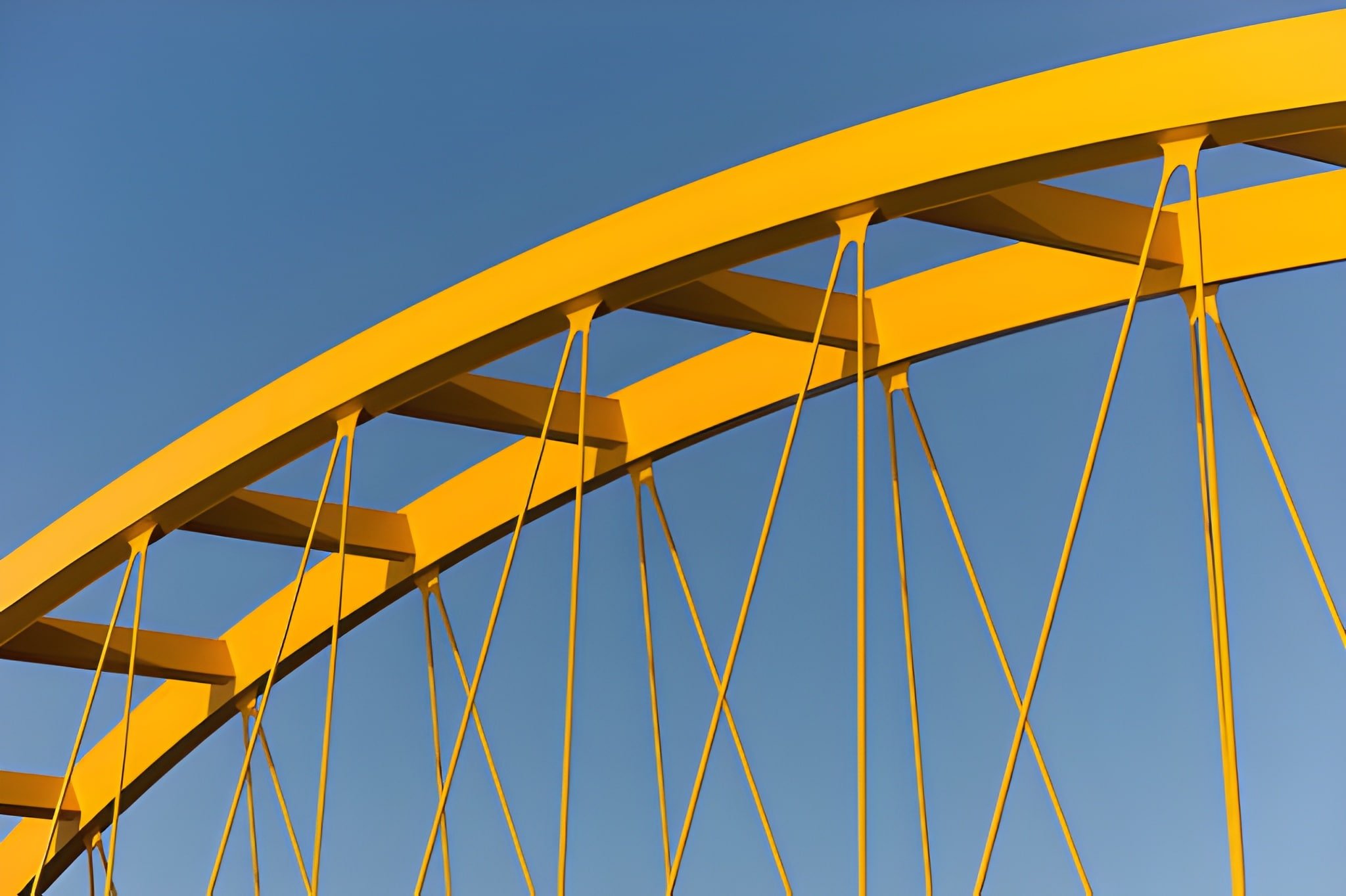 Close-up of a yellow amusement park ride structure against a clear blue sky.