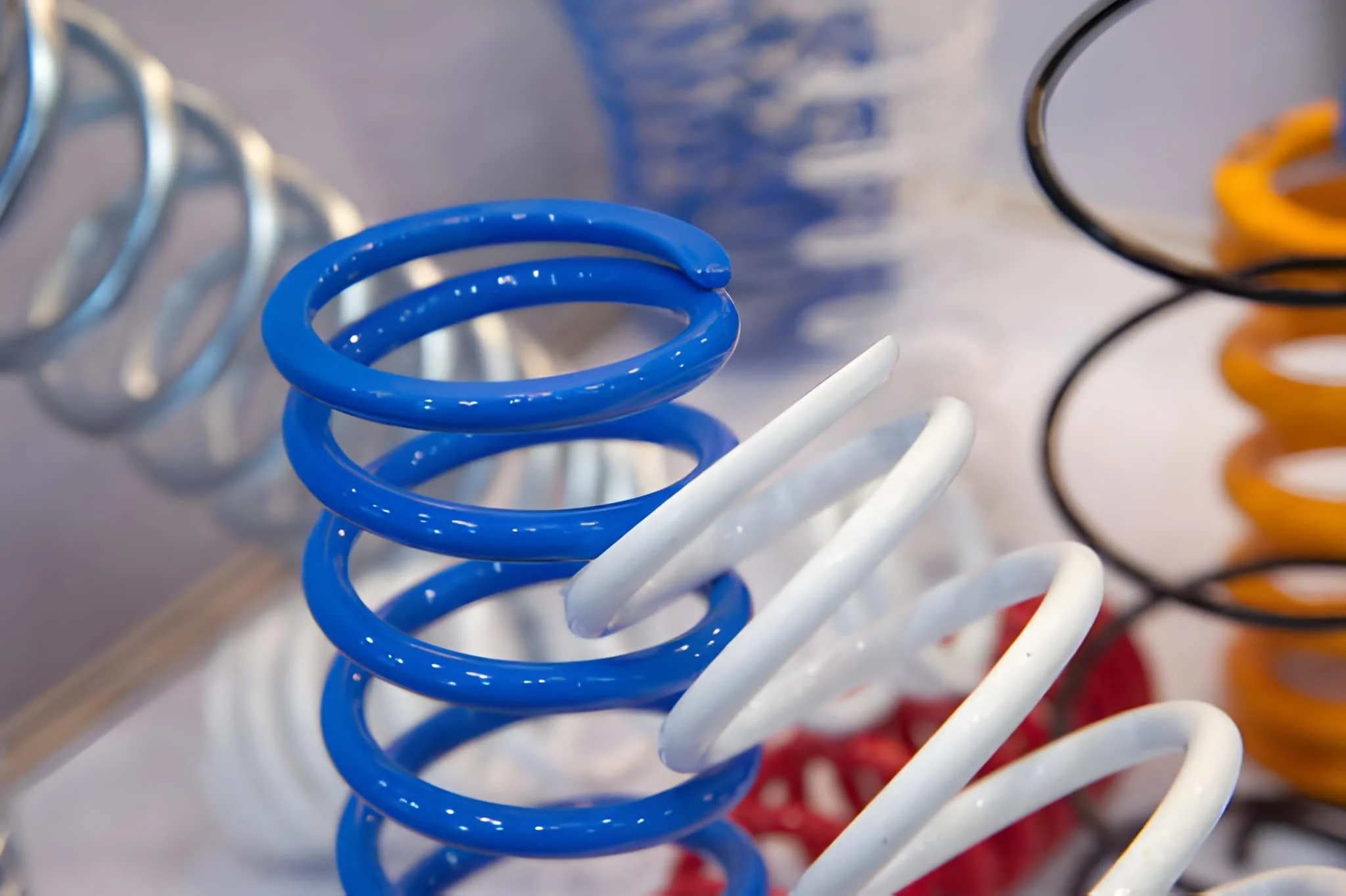 Close-up of colorful coil springs, including blue and white, on a display rack.