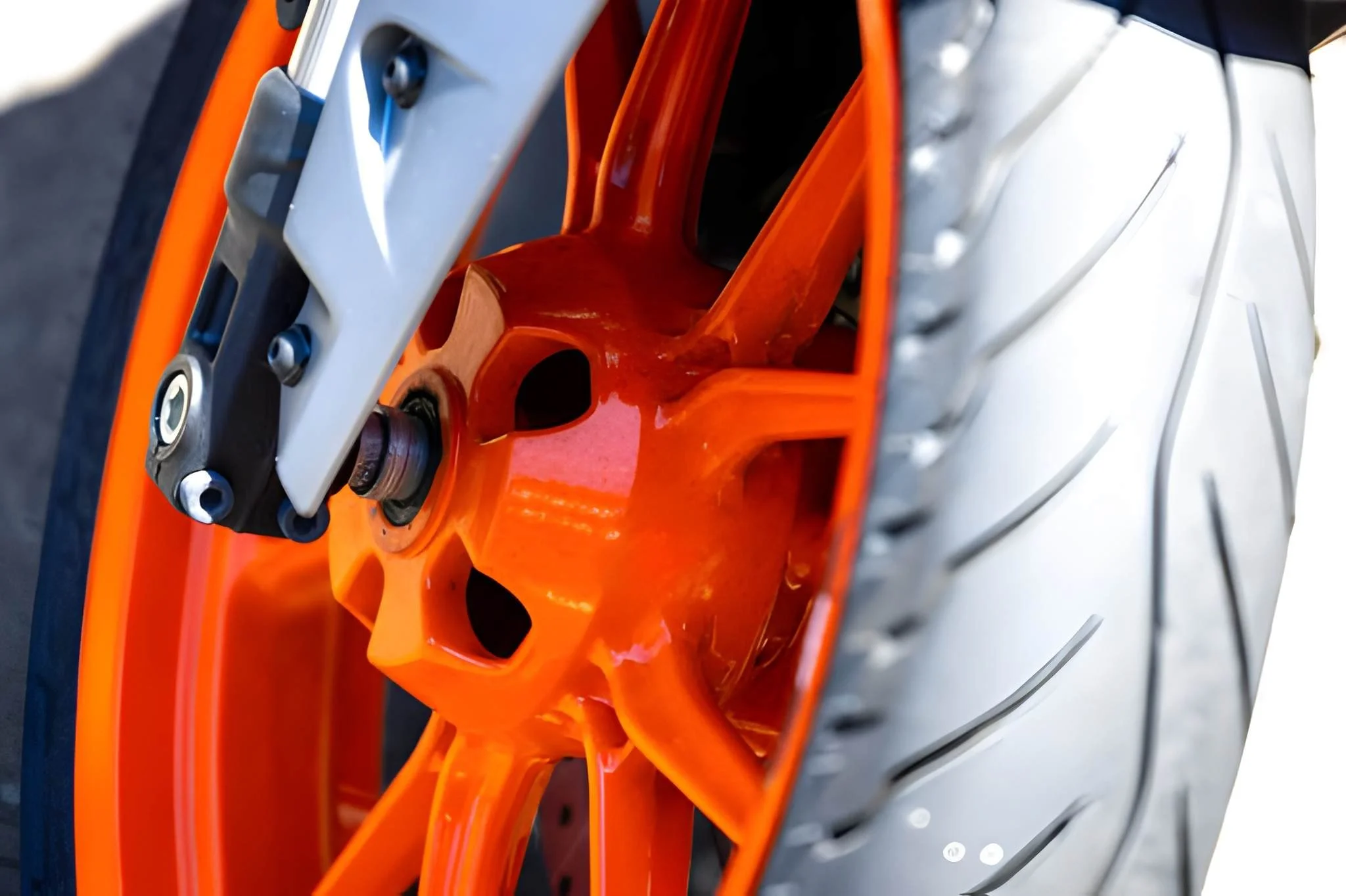Close-up of a motorcycle front wheel showing an orange rim, a gray front fork, and a silver brake disc.