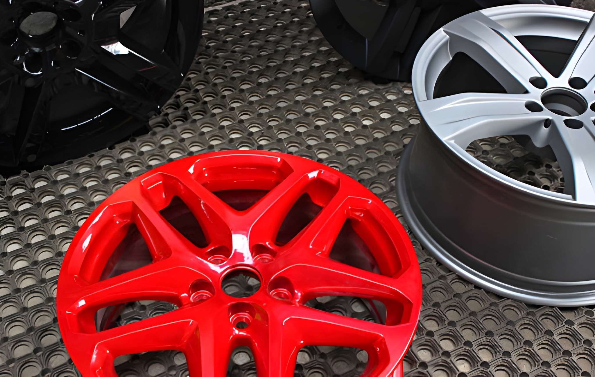 An assortment of colorful car wheel rims on a textured floor.