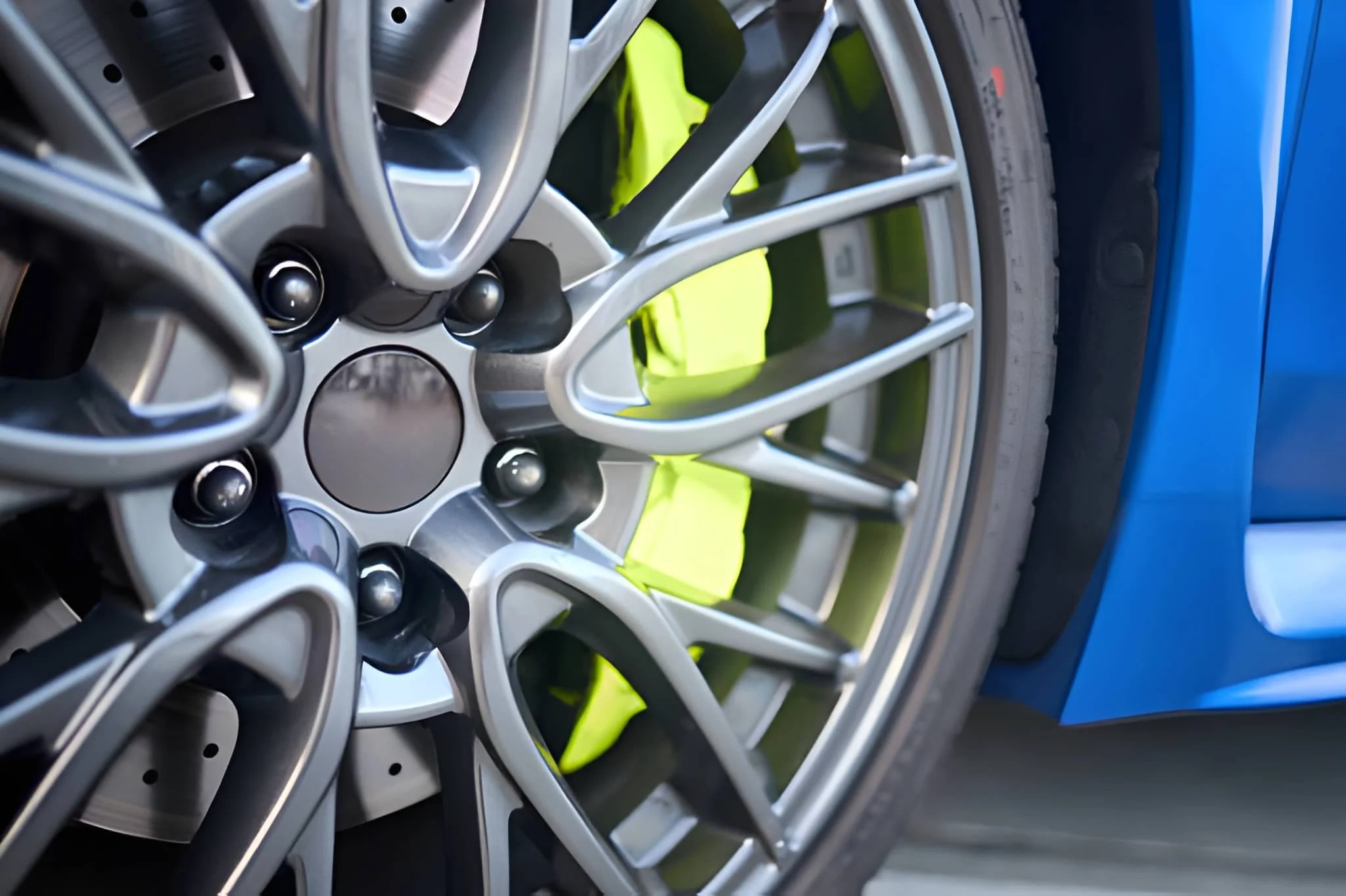 Close-up of a blue sports car wheel with a detailed silver alloy rim and a tire.