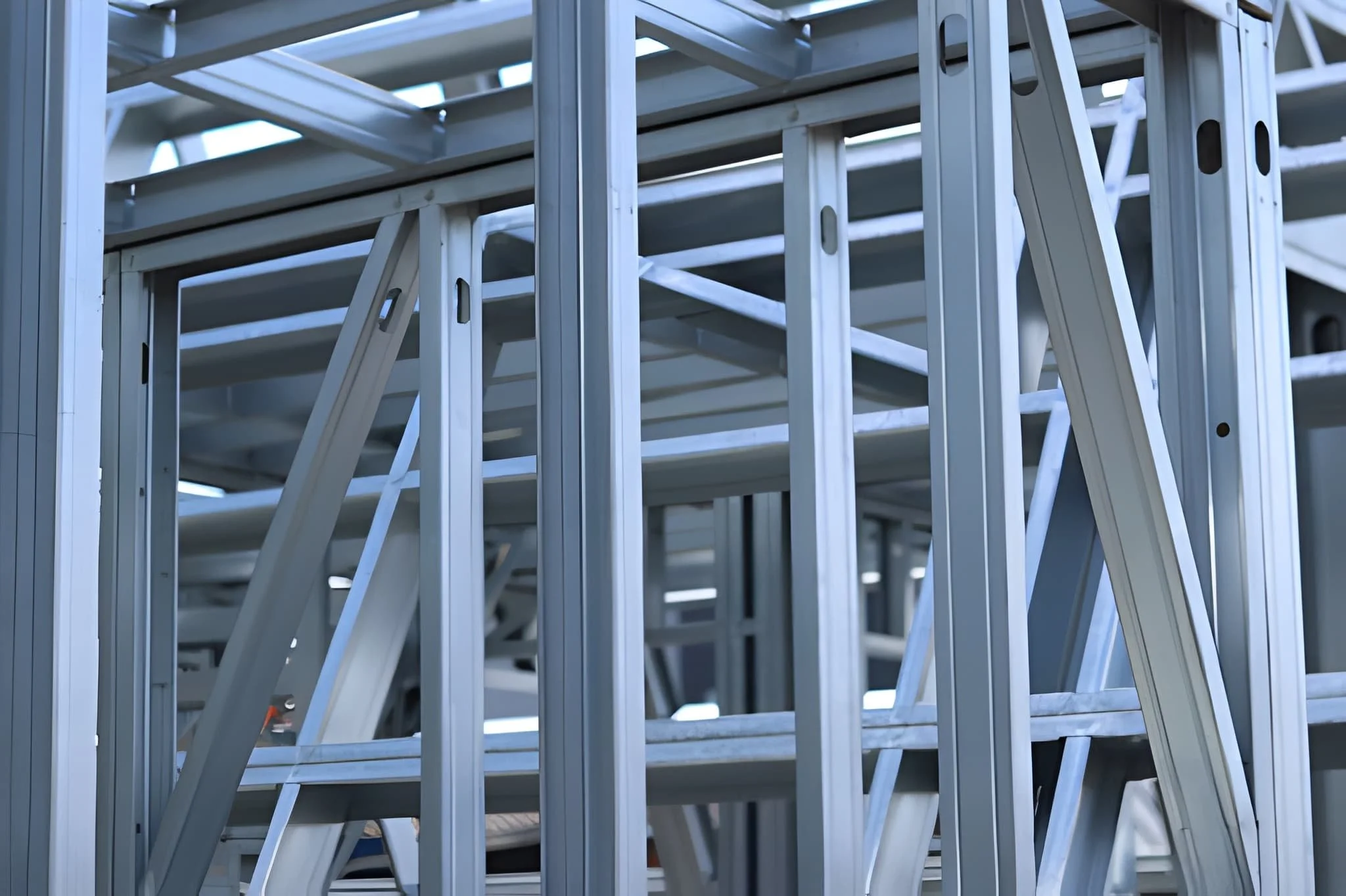 Stacked aluminum ladders stored outdoors.