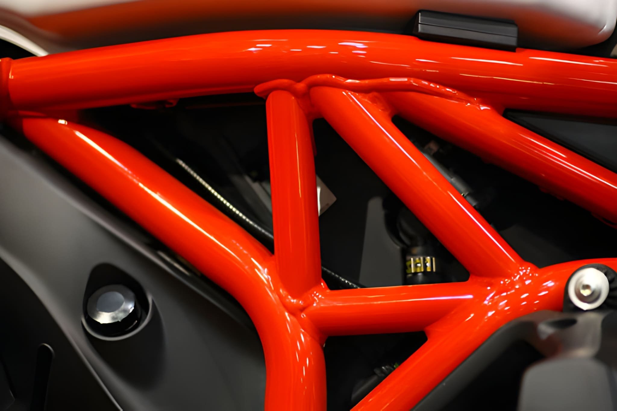 Close-up of a bright orange bicycle frame inside a bicycle shop or storage area.