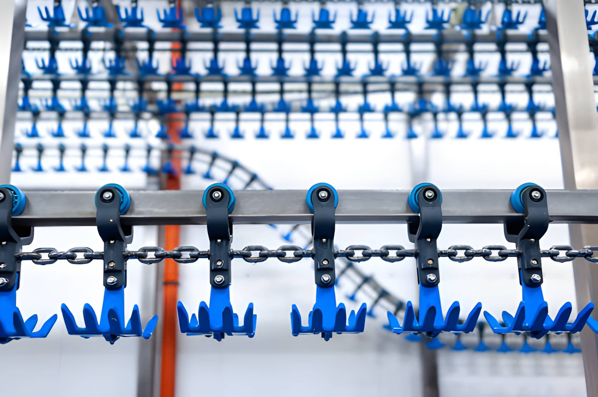 Close-up of blue plastic hooks and chains on a metal rack, with another rack of similar hooks in the blurry background.