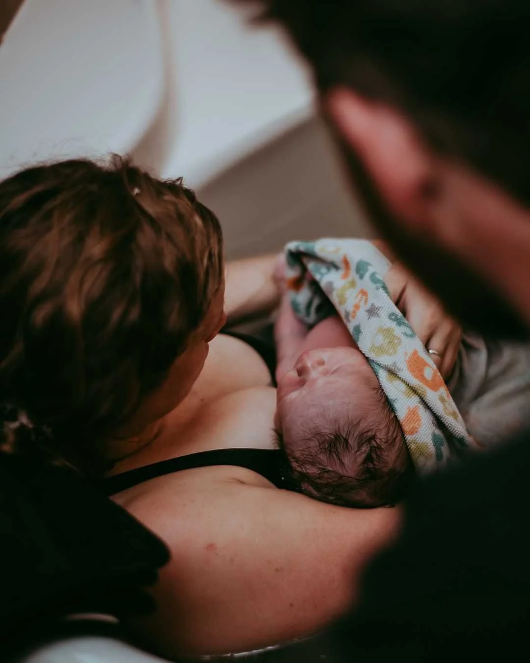A woman giving birth, holding her newborn baby after delivery.