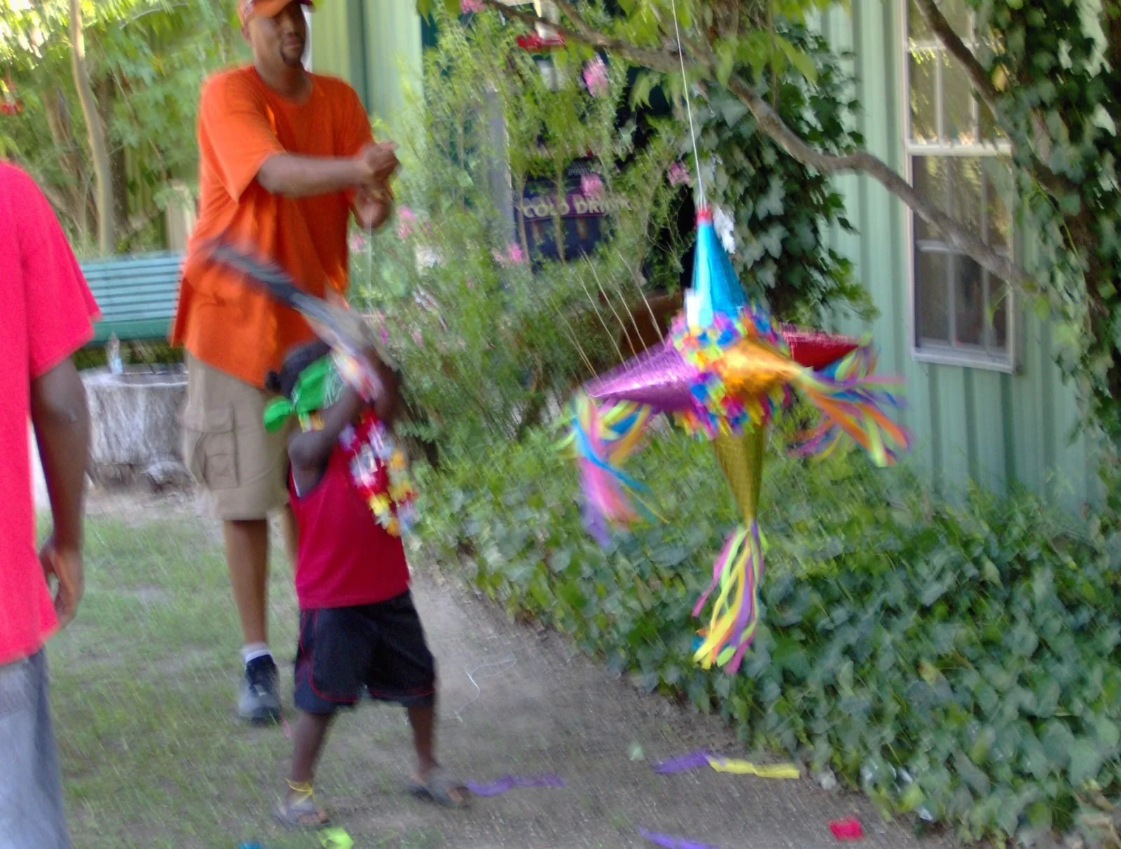 Family flying a colorful piñata outdoors on the ground.