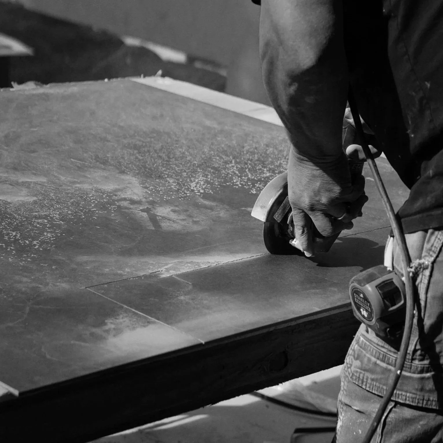 A person using a handheld power saw to cut a piece of material on a work table in a workshop.