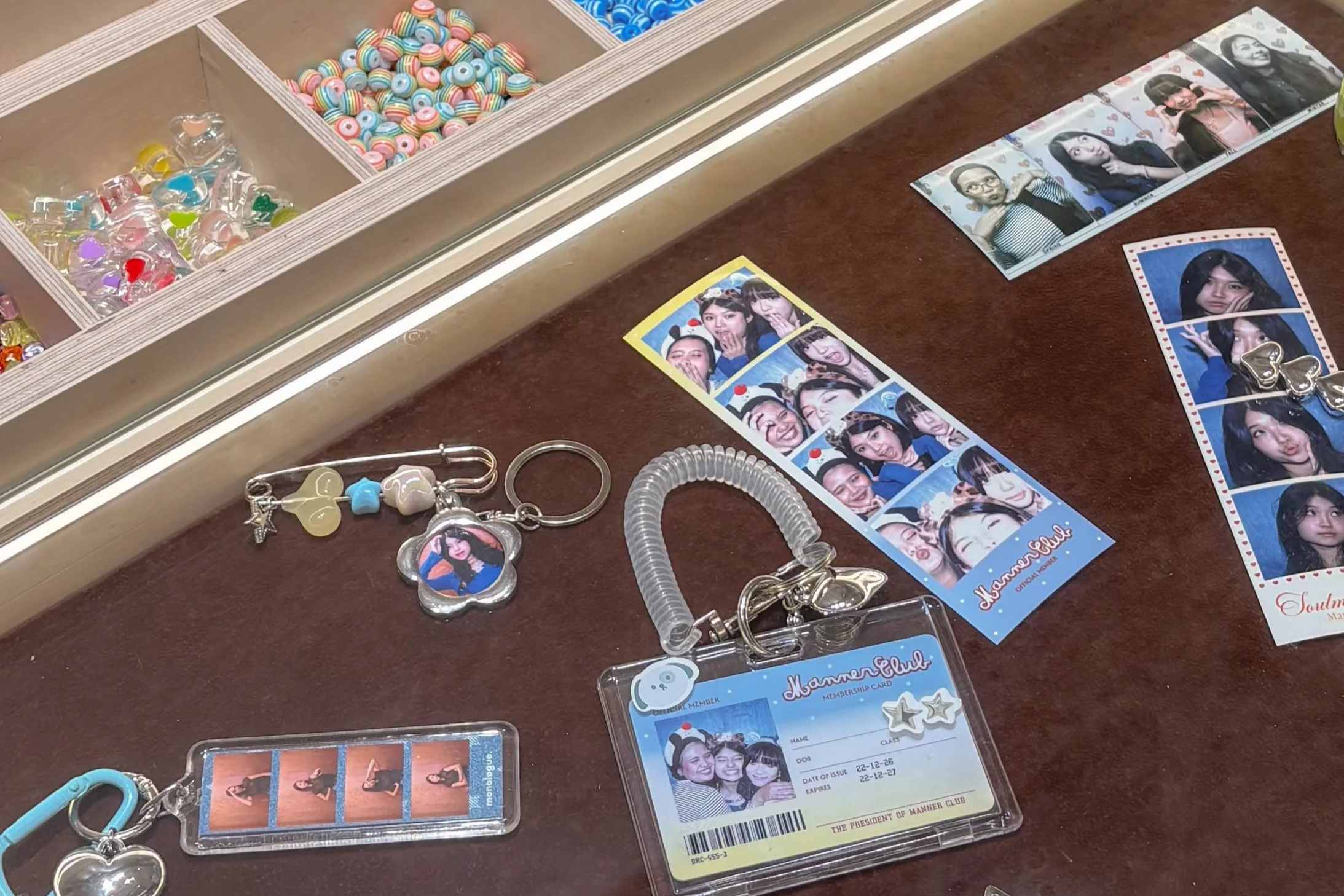 Photobooth props and photo strips with pictures of young women, often making playful faces, along with a card indicating membership in the Manner Club.