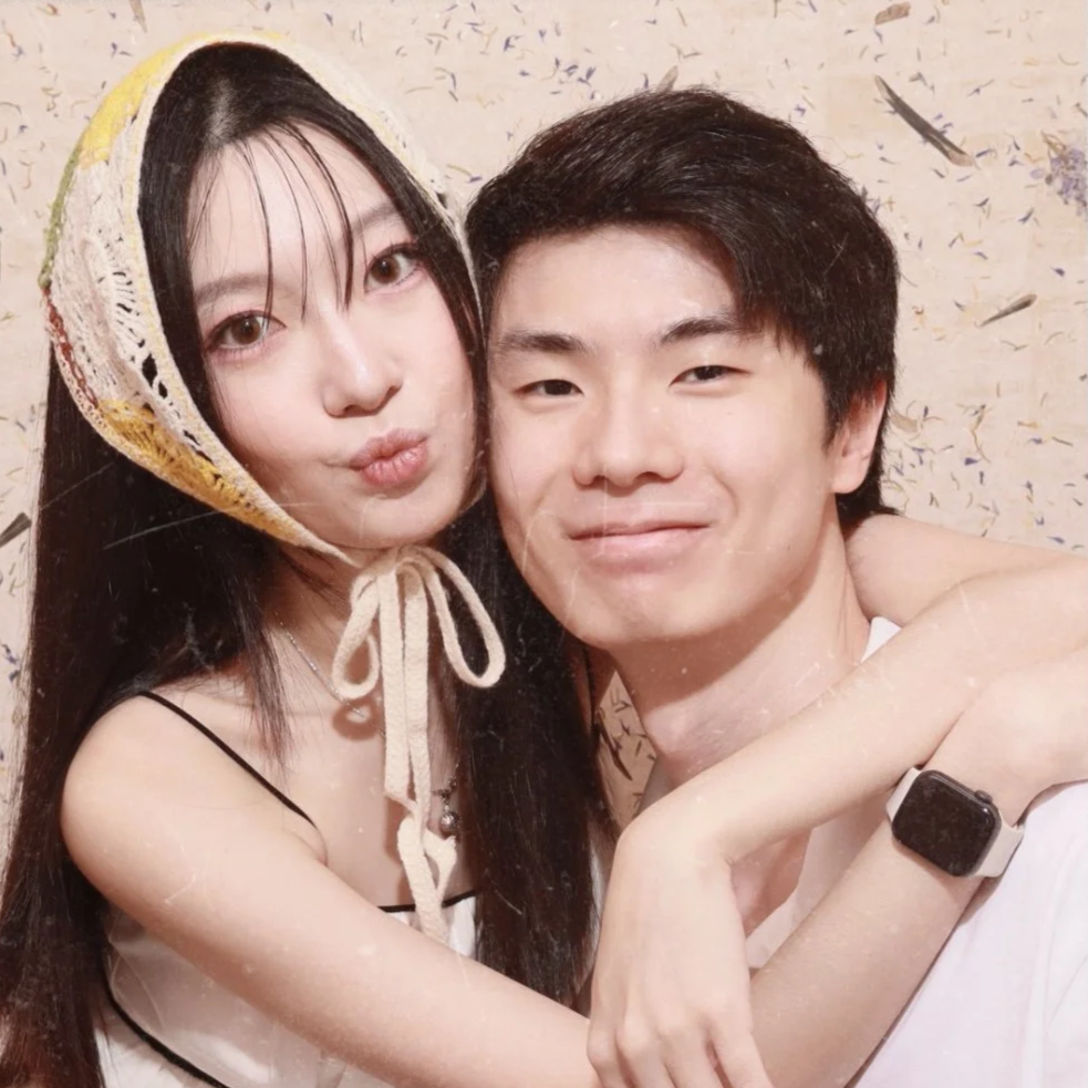 A young woman and a young man taking a close-up selfie together, smiling and hugging each other, with confetti in the background.