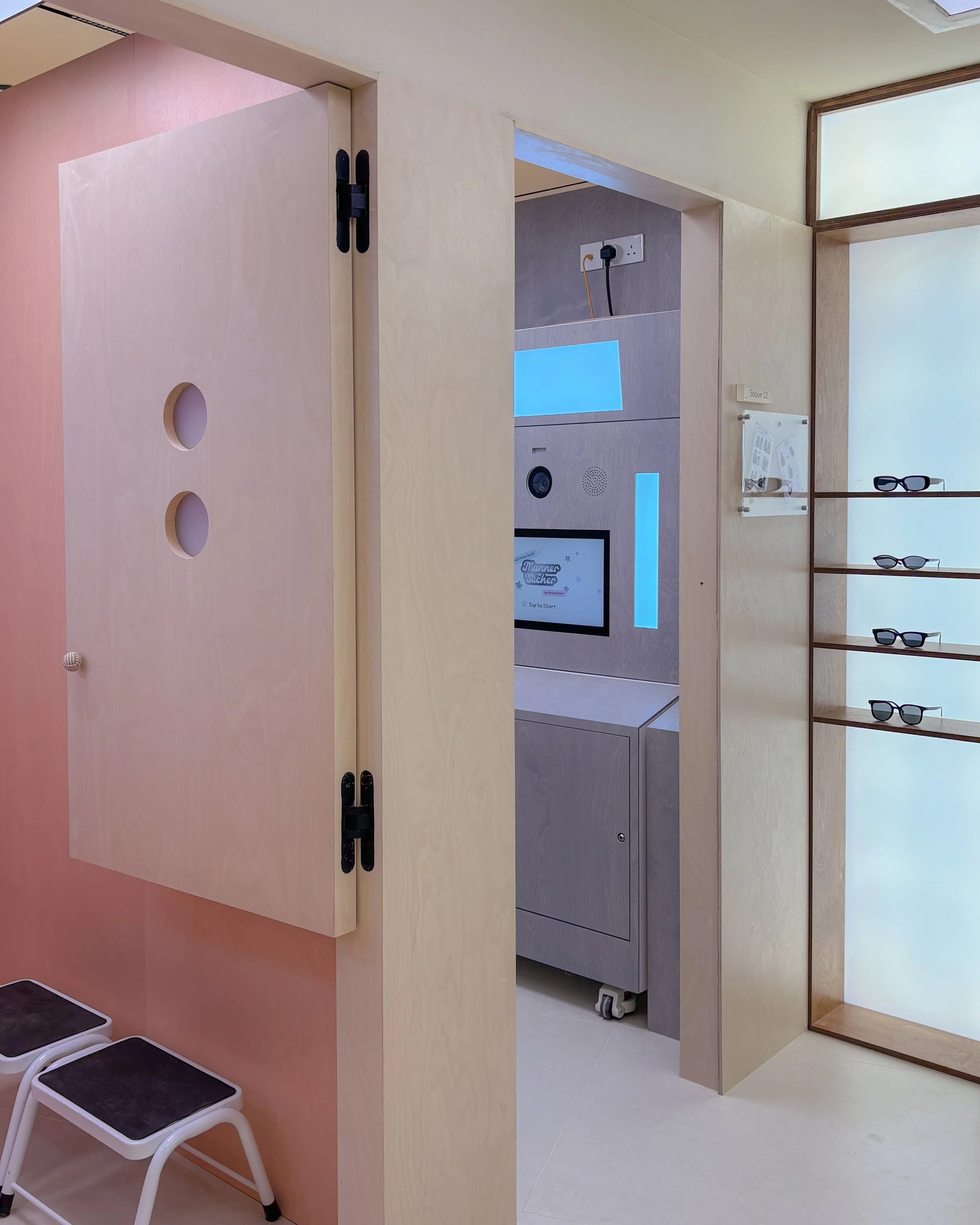 Interior of a medical waiting area with a privacy partition, chairs, and a display screen showing the text 'Manners Stacker'.