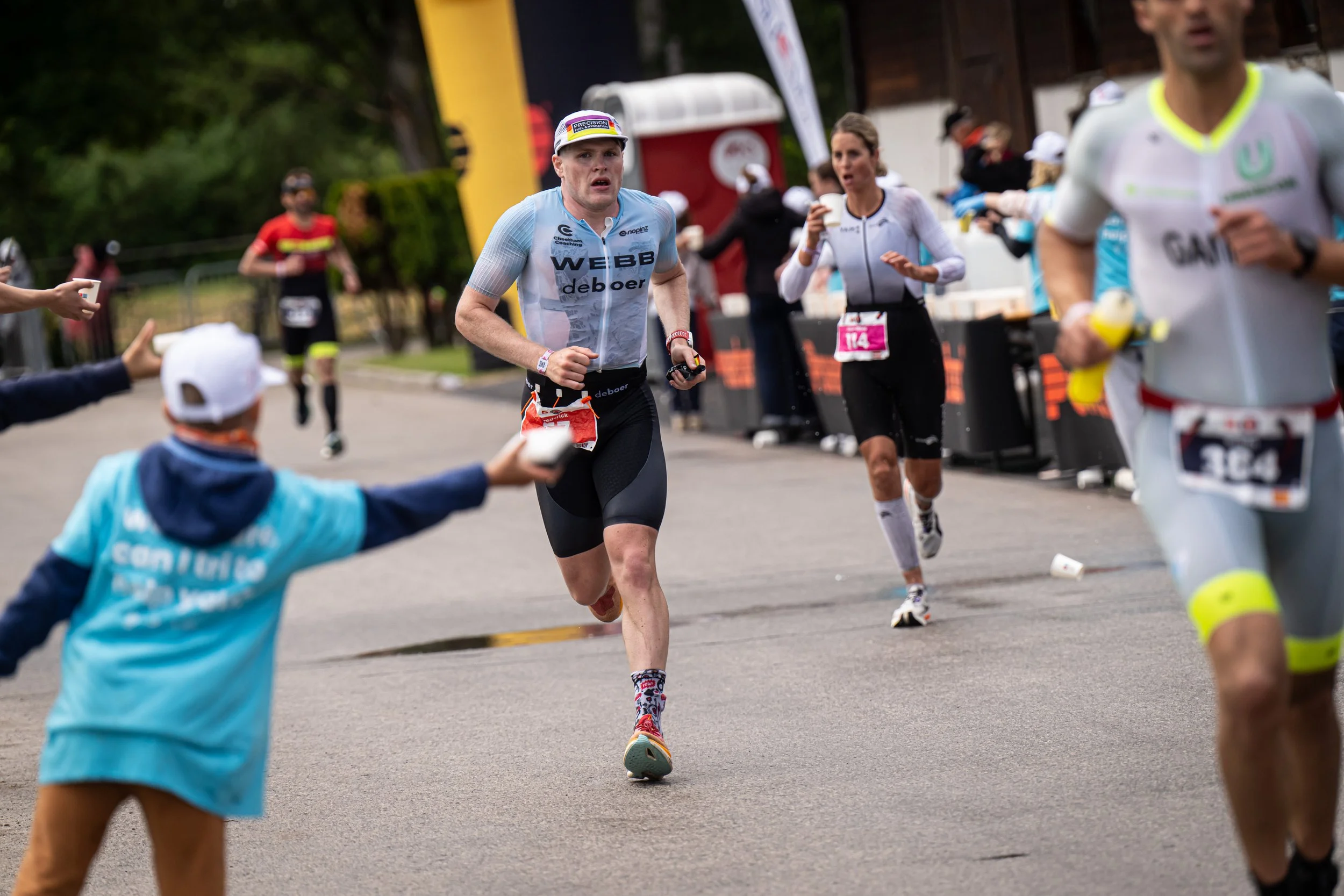 Marathon runners participating in a race, with spectators holding out water bottles and cups along the roadside.