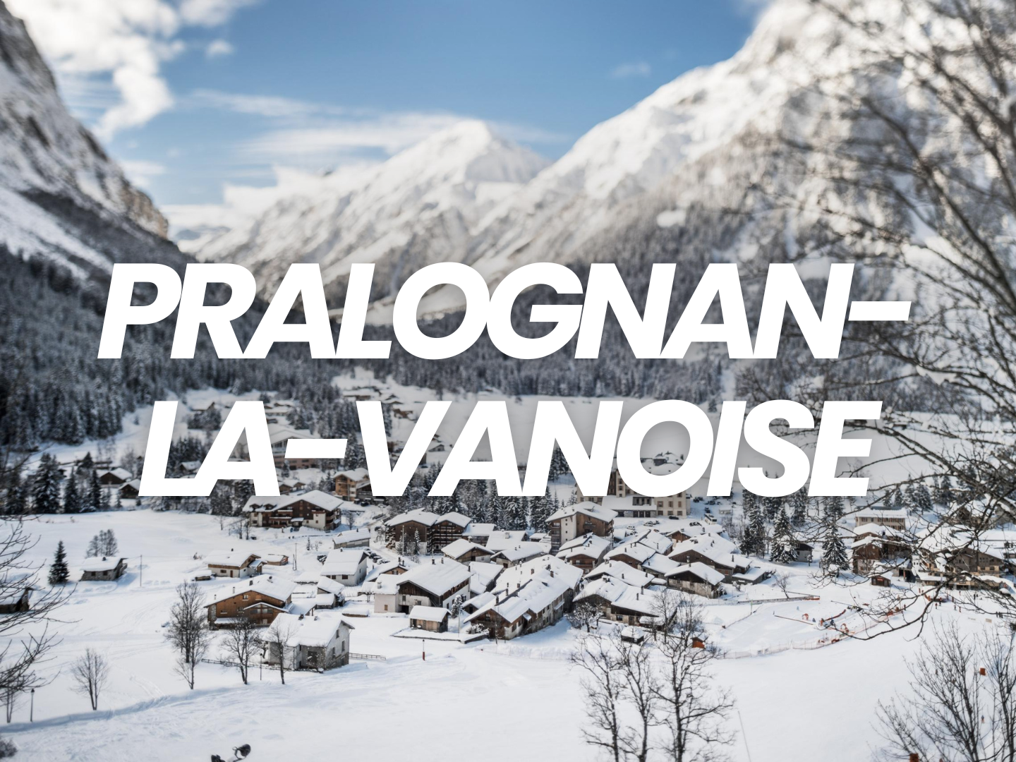 Village enneigé dans une vallée entre des montagnes avec arbres nus en hiver.