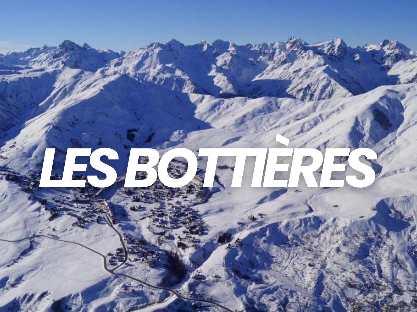 Vallée enneigée entourée de hautes montagnes avec un ciel clair, où un petit village est visible dans la neige, avec le texte 'Les Bottières' en gras blanc.