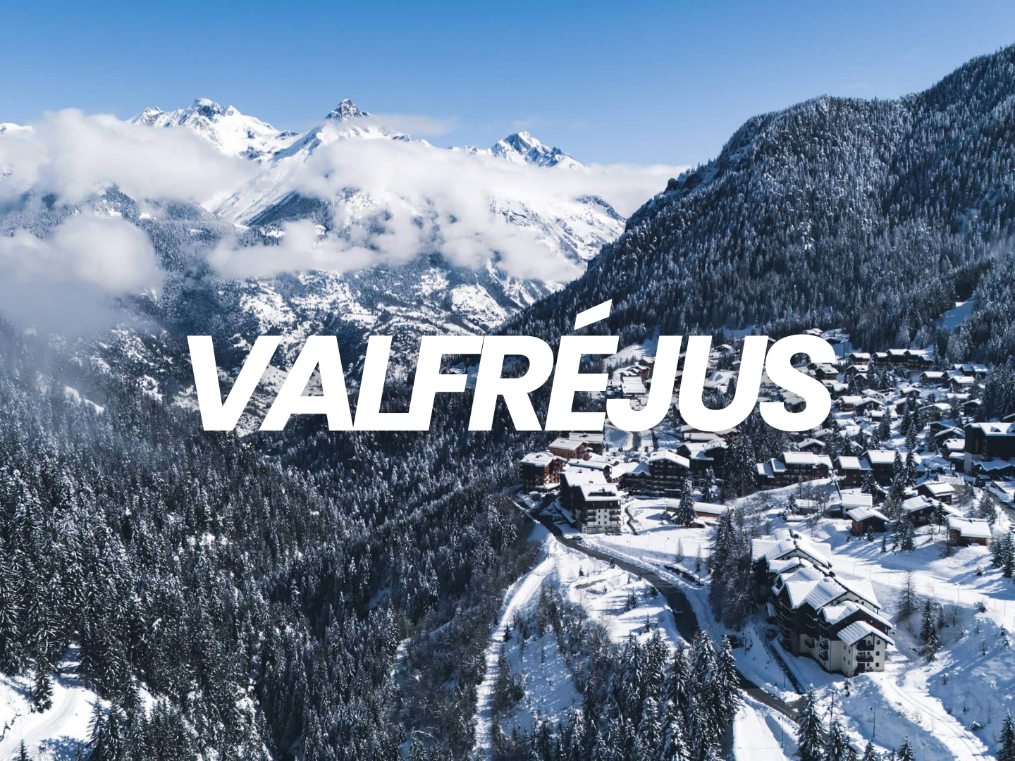 Vue aérienne d'un village de montagne enneigé dans les Alpes françaises avec des sommets enneigés et des forêts.