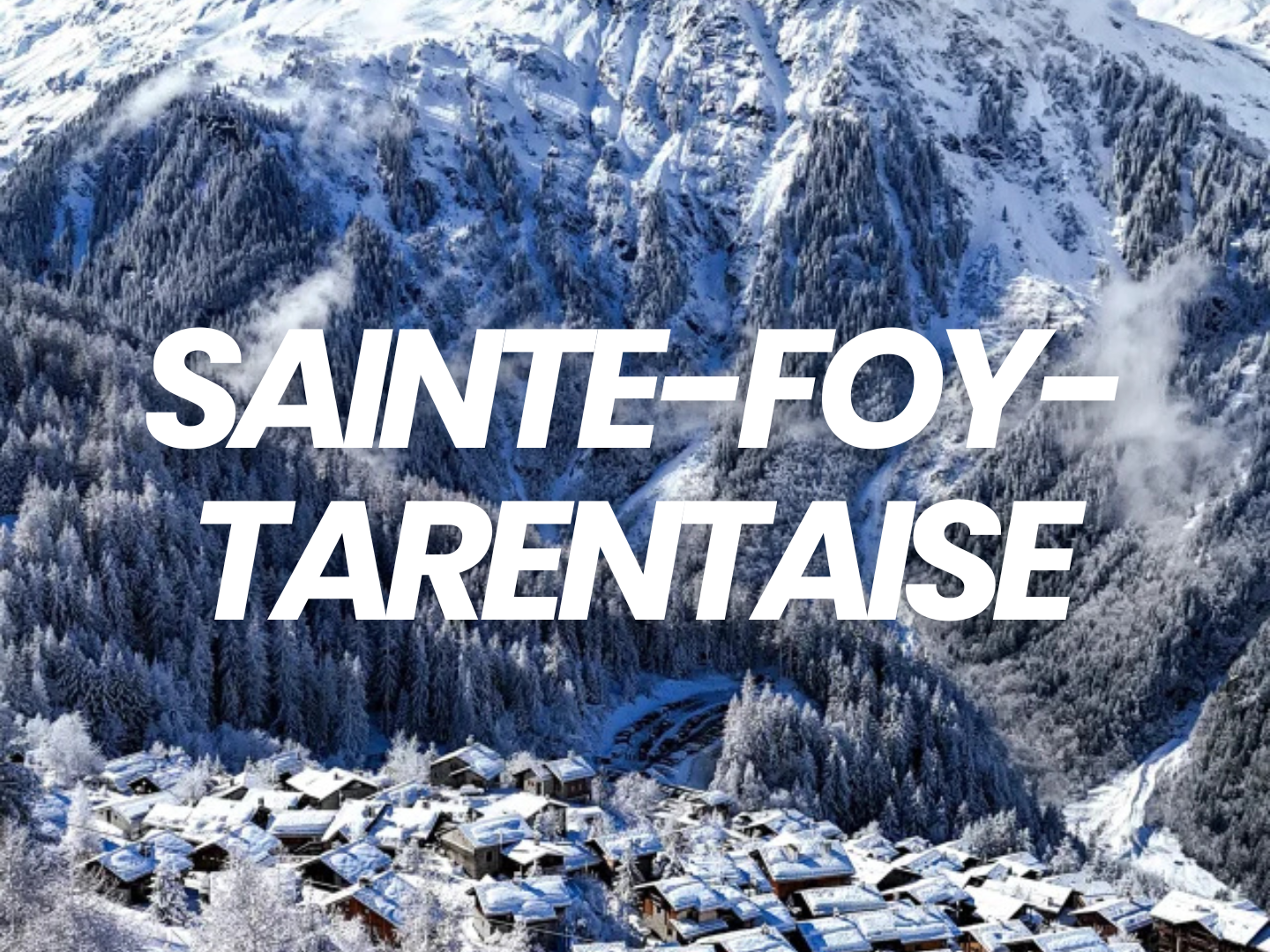 Village enneigé au pied de montagnes couvertes de forêts, avec du brouillard et un ciel clair, en Savoie, France.