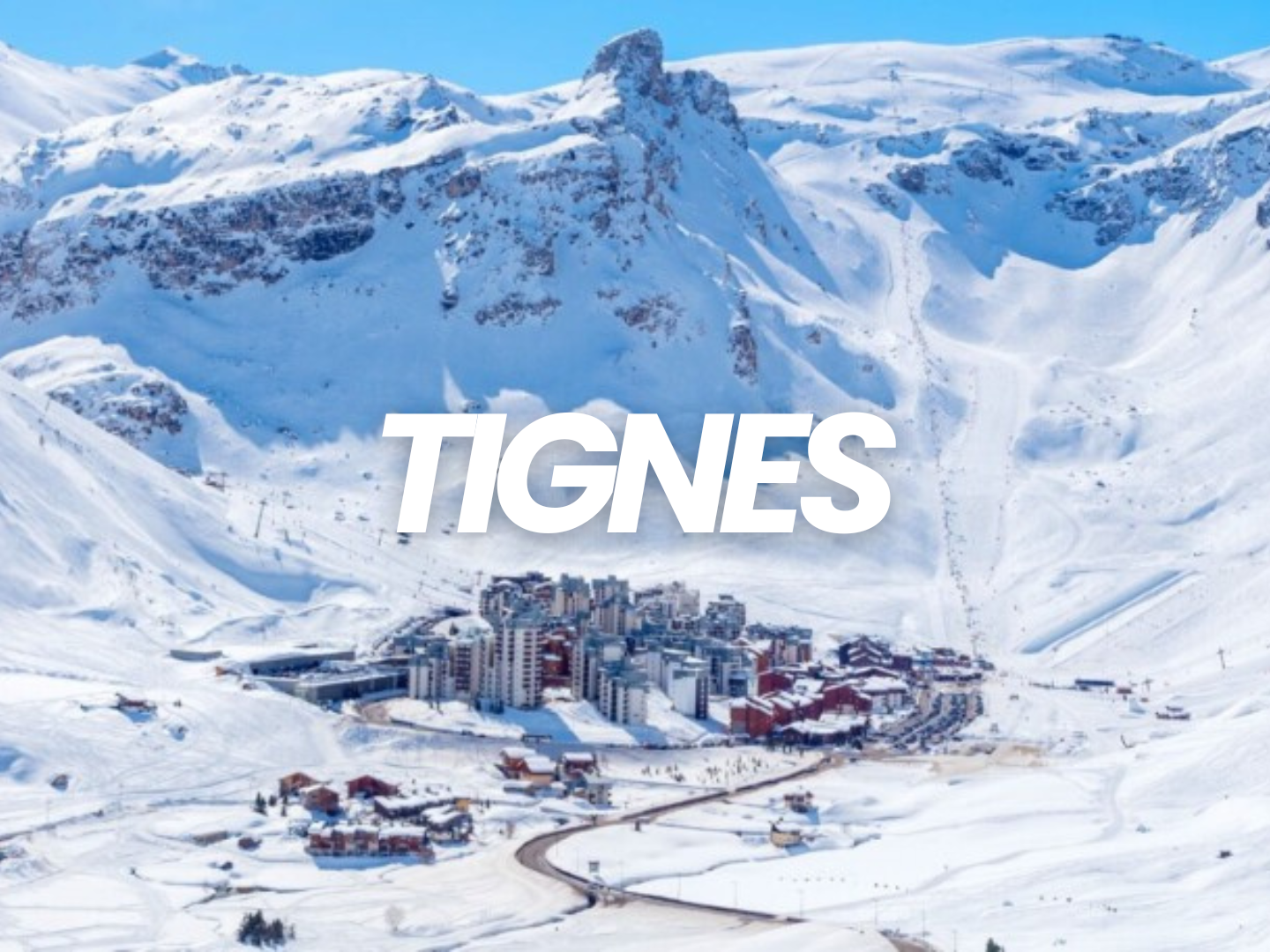 Station de ski de Tignes dans les Alpes françaises, entourée de montagnes enneigées, avec un village en bas et des pistes de ski.
