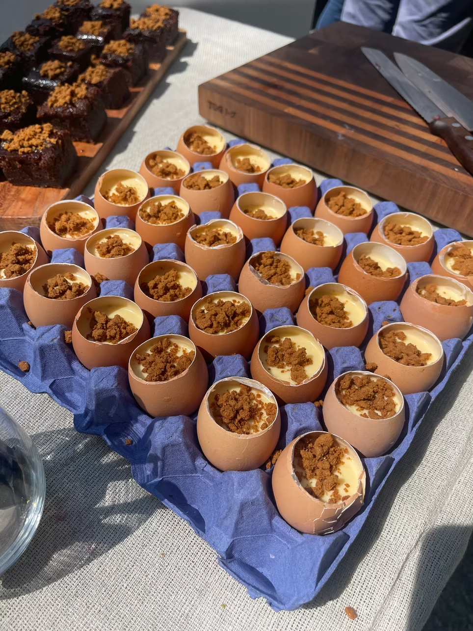 Deviled eggs topped with crumbled cookie or cracker topping on a blue tray.