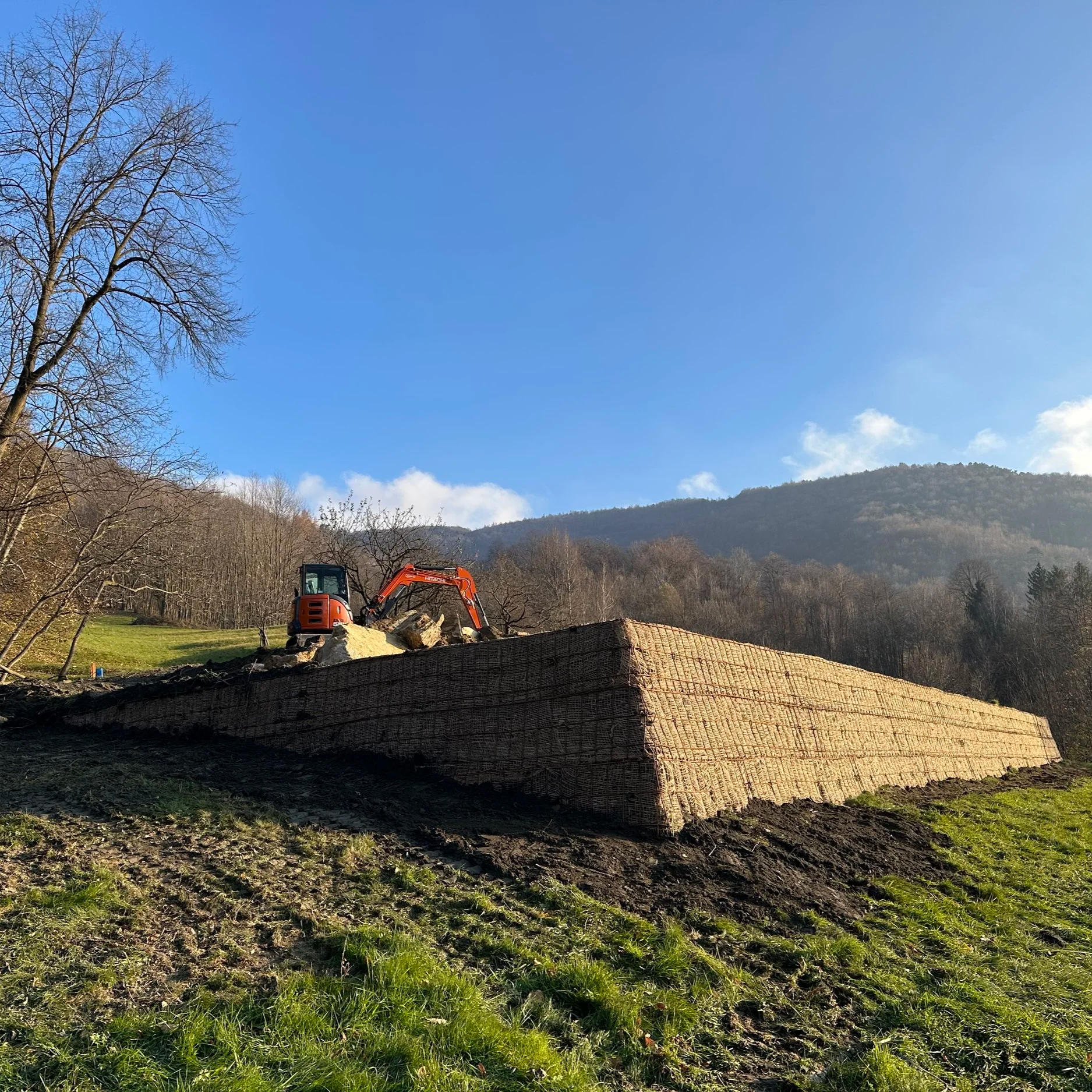 Cantiere con una pompa escavatore e grandi mattoni di terra in montagna con cielo blu