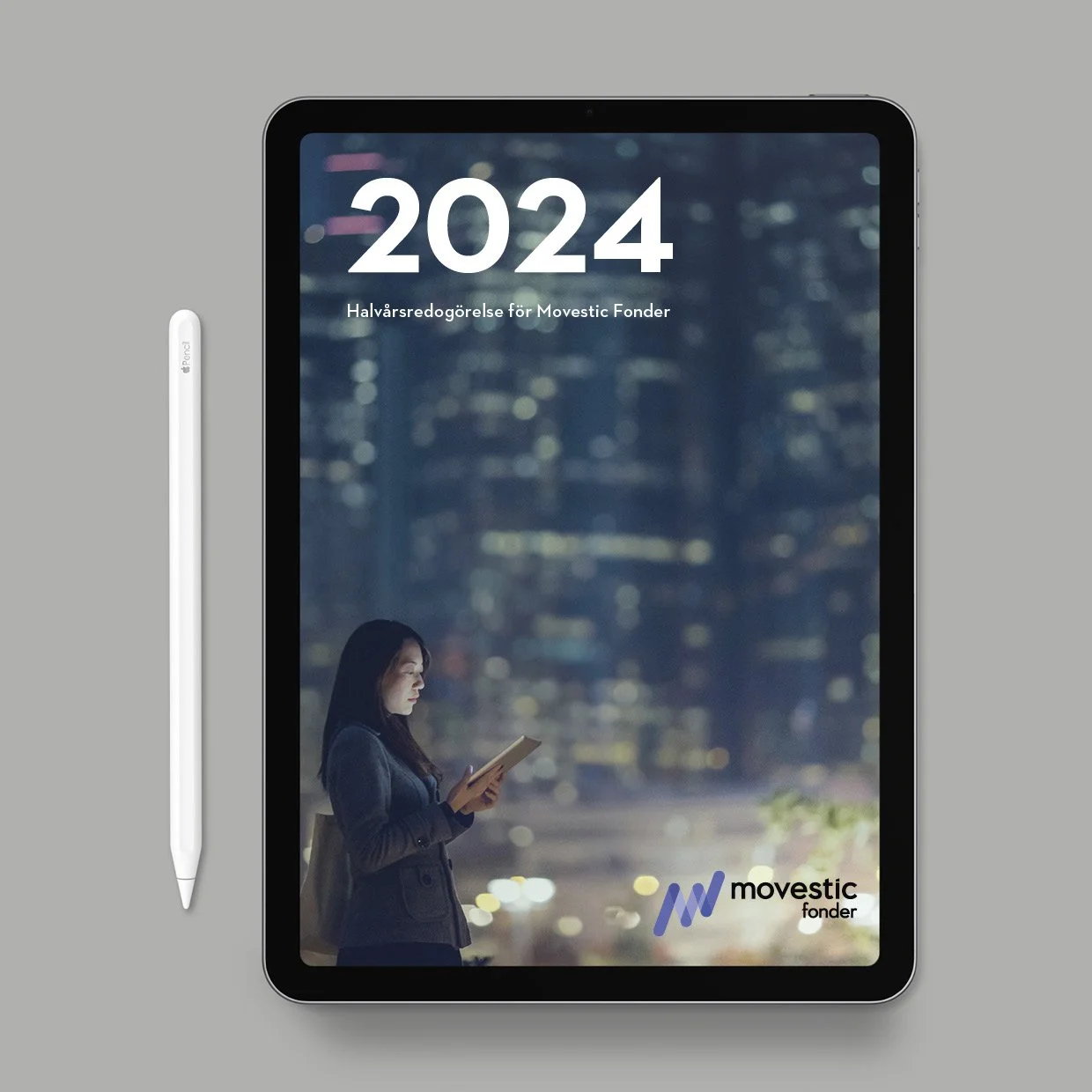 An iPad displaying a report titled '2024 Halvårsredogørelse för Movestic Fonder' with the Movestic Fonder logo at the bottom right. A woman in business attire is looking at her phone, with a blurred cityscape background. A white Apple Pencil is placed to the left of the iPad.