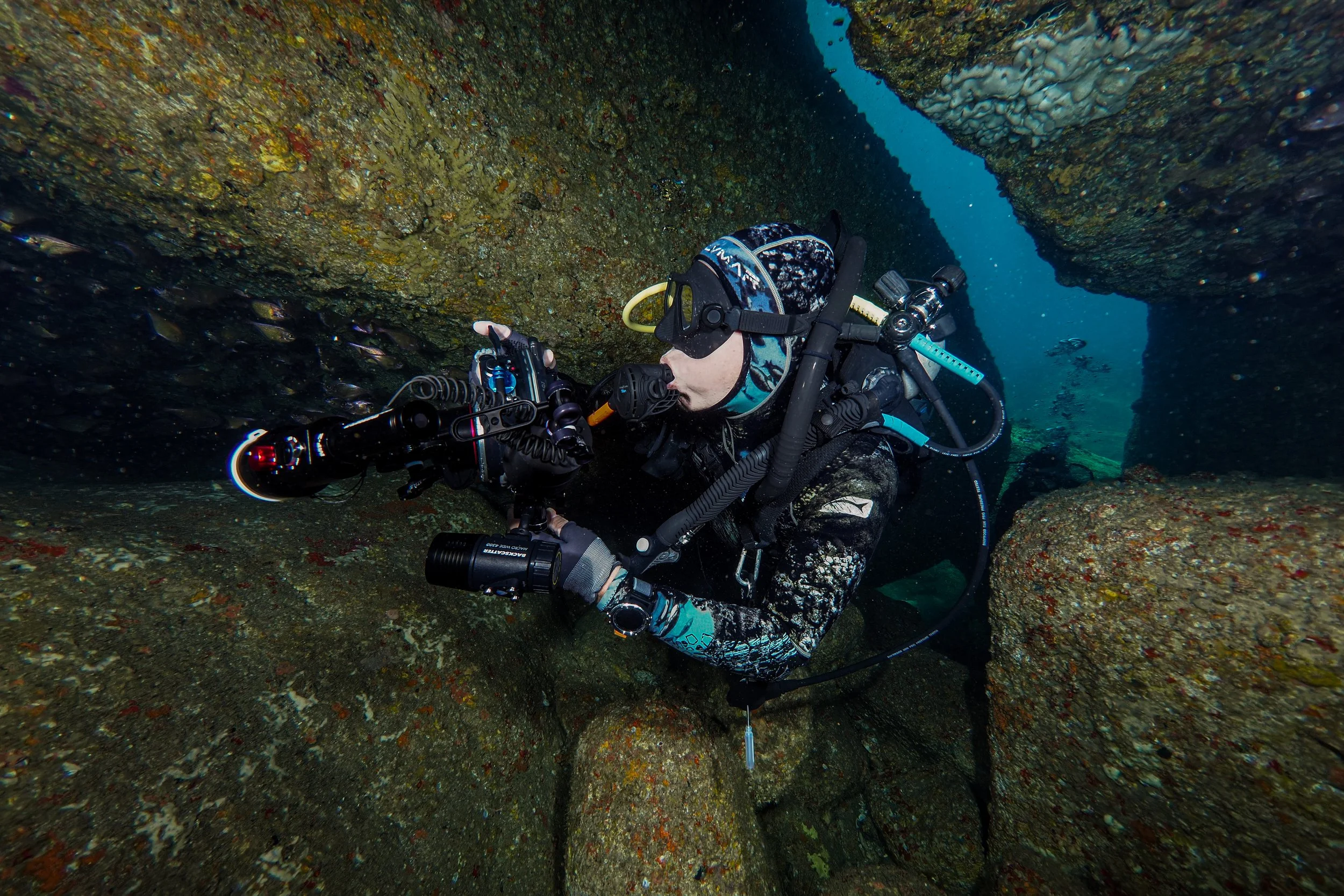 A scuba diver exploring underwater rocks and formations.