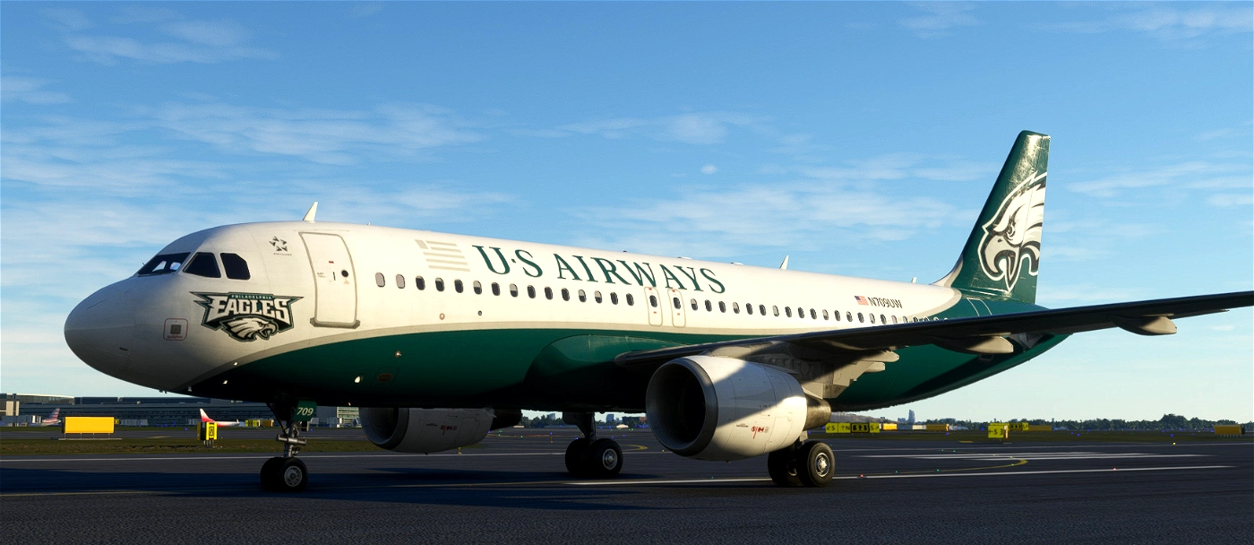 Passenger airplane with U.S. Airways livery featuring a Philadelphia Eagles logo on the front and eagle head graphic on the tail, taxiing on the runway at sunset.