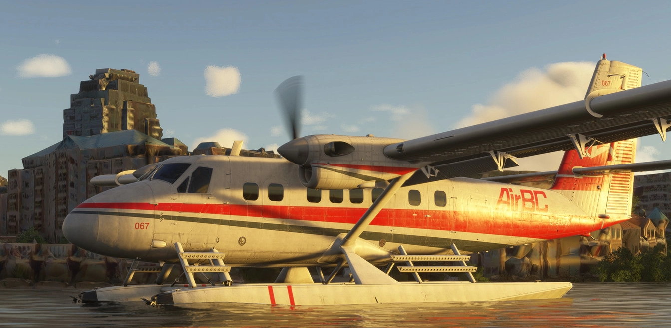 Seaplane floating on water in front of colorful buildings with cloudy sky.